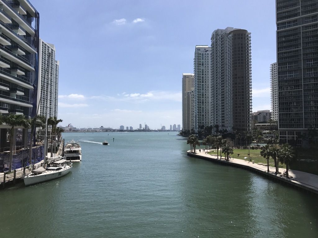 A wide waterway with boats, flanked by tall buildings under a bright sky. - Miami Baywalk and Riverwalk