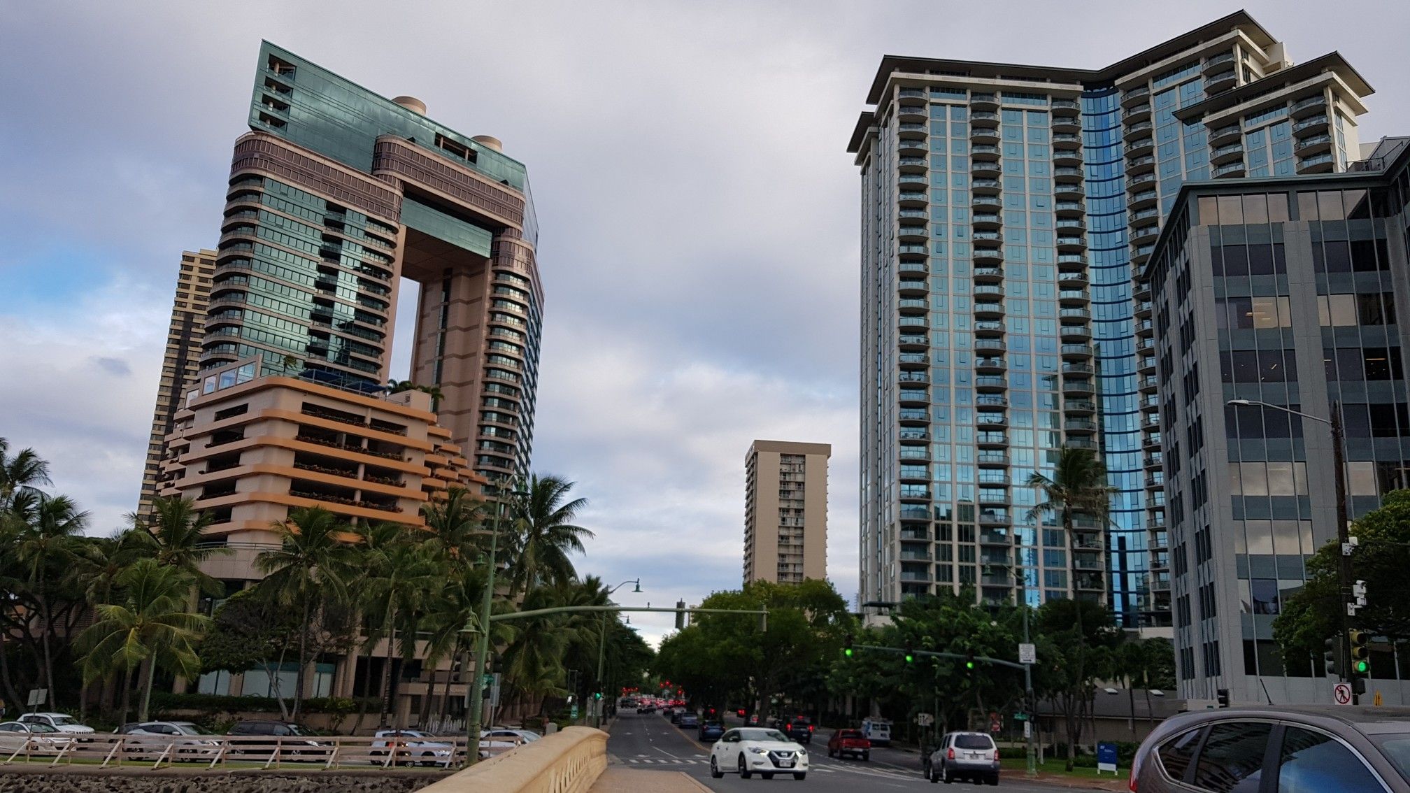 Modern city buildings, busy street with cars, and palm trees. - Giant fig tree – King Kamehameha Statue loop from Honolulu