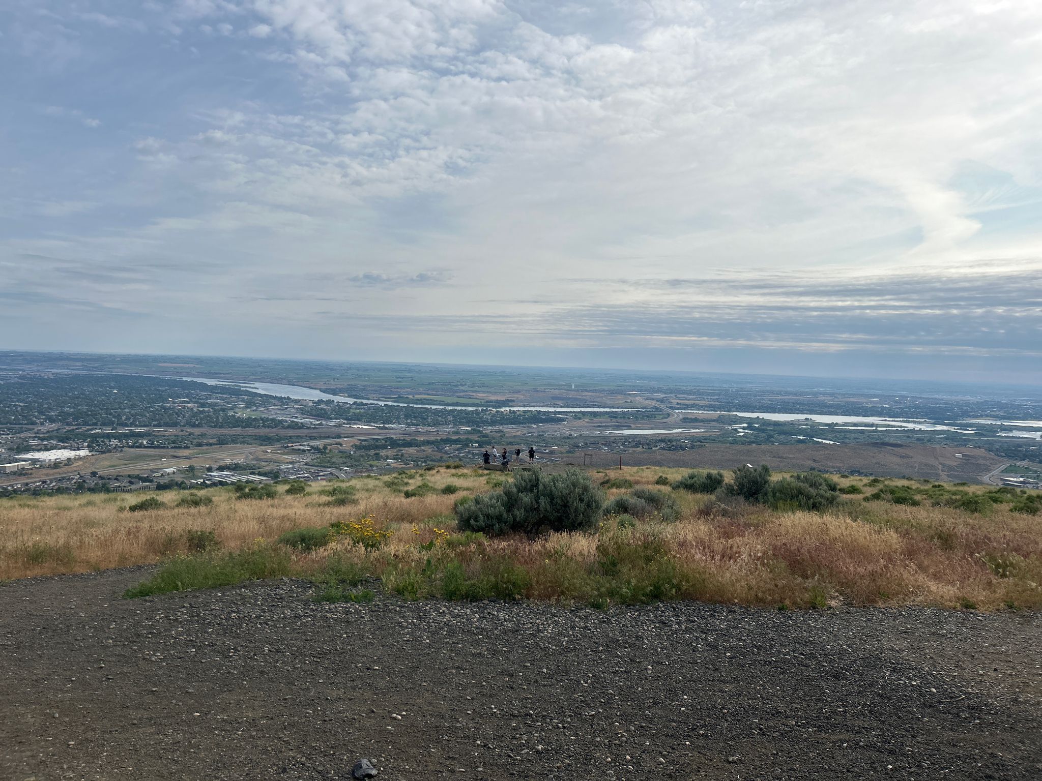 Group of people on a grassy hill overlooking a distant city and river. - Sagebrush Trail – View of Badger Mountain loop from Badger Mountain Centennial Preserve