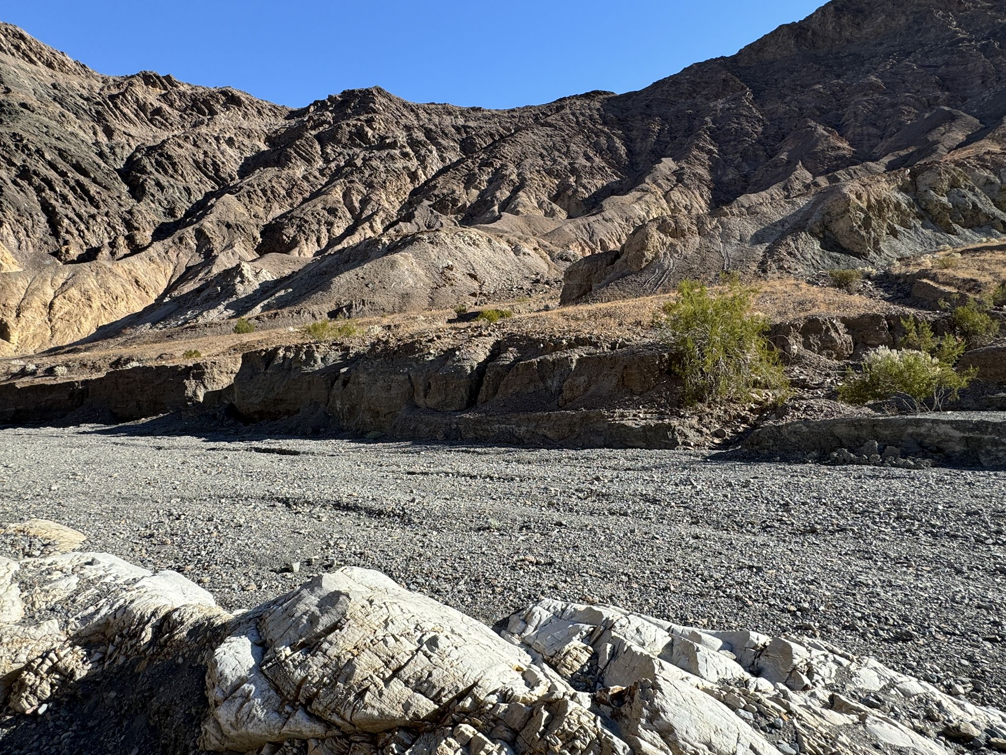 Wide dry wash with rugged mountains under a clear blue sky. - Mosaic Canyon Trail