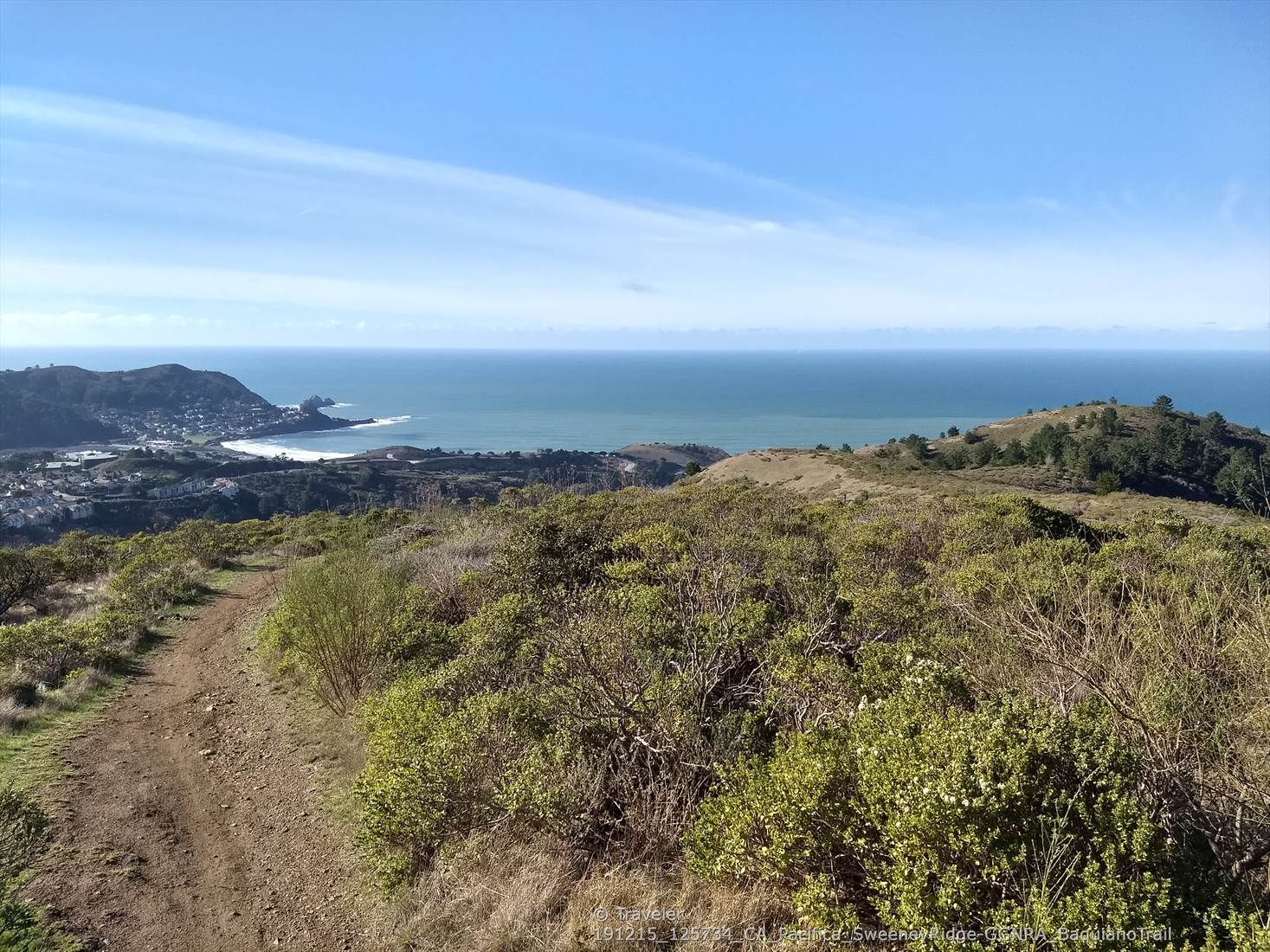 A dirt path on a green hill overlooks a bay and distant ocean. - Farallones Trail Lookout loop from Pacifica