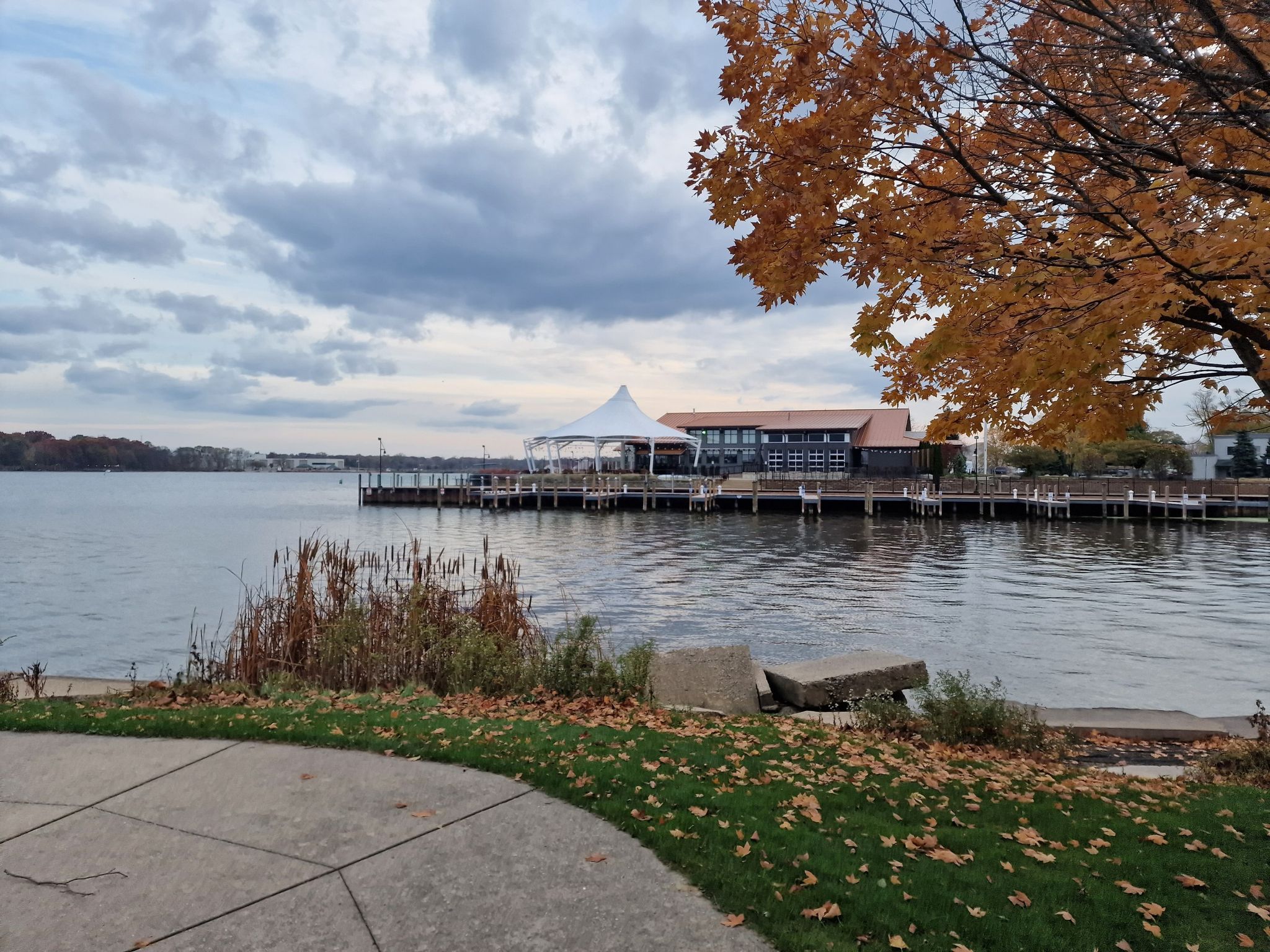 Overcast view of a lake with docks, a building, and autumn trees. - Kollen Loop