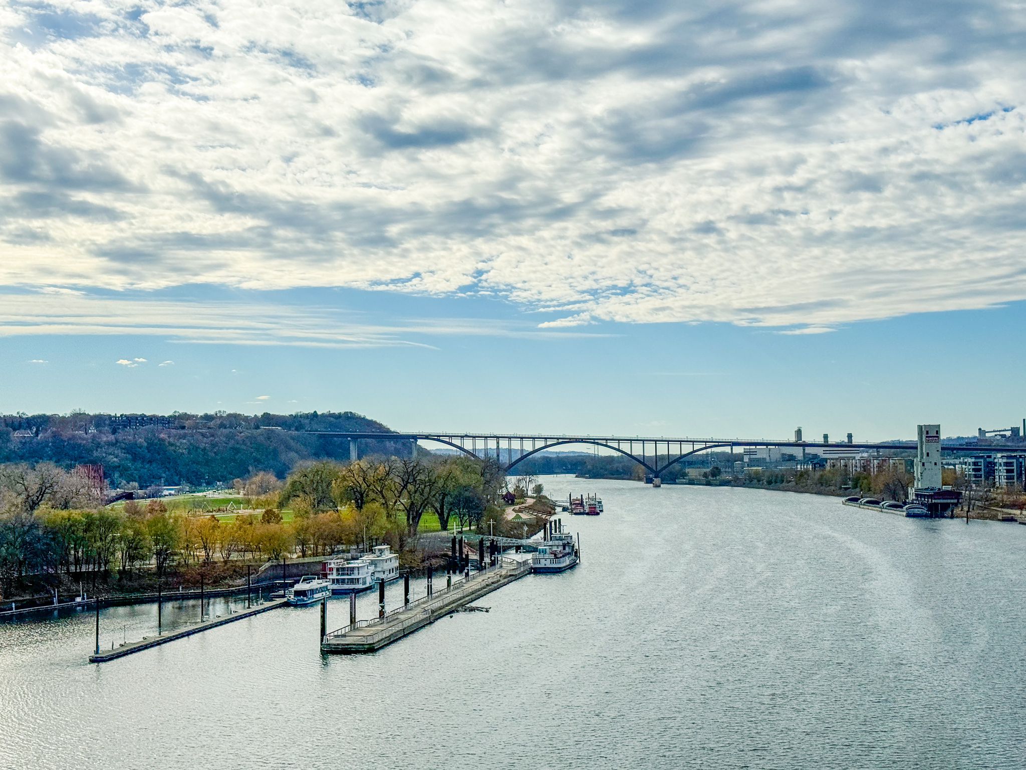Wide river with docks, boats, and a large bridge under a cloudy sky. - St. Paul to Rice Creek Chain of Lakes Park loop