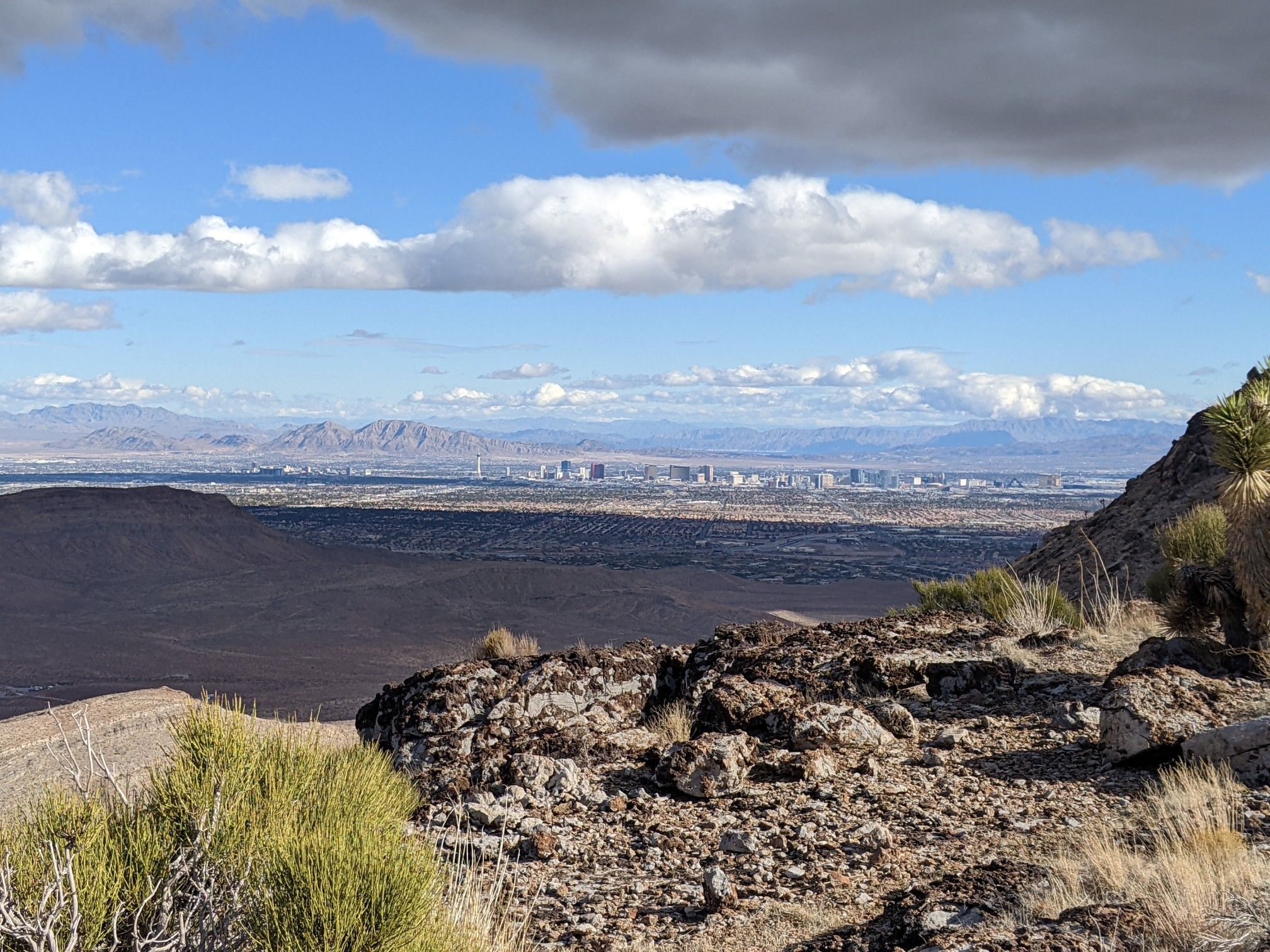 Rocky desert viewpoint overlooking a distant city and mountains under cloudy sky. - Las Vegas Overlook Loop