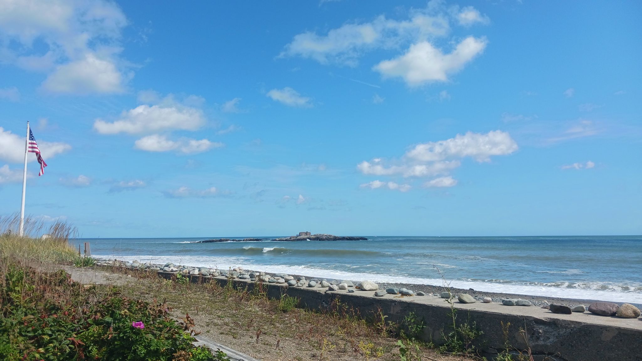 Bright beach scene with ocean waves, an American flag, and blue sky. - Wompatuck State Park loop from Weymouth