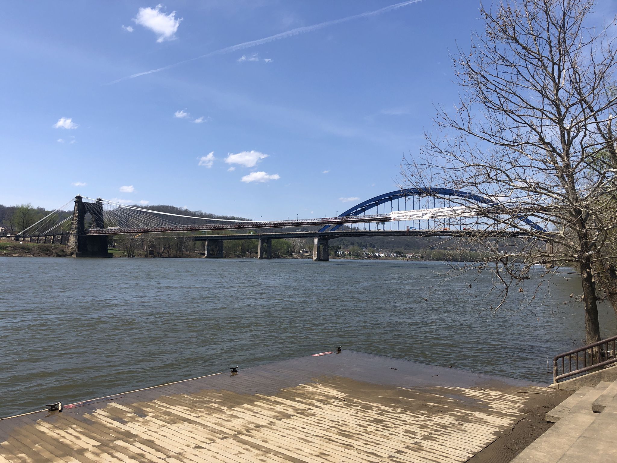 Two bridges span a wide river under a bright blue sky. - Wheeling Heritage Trail
