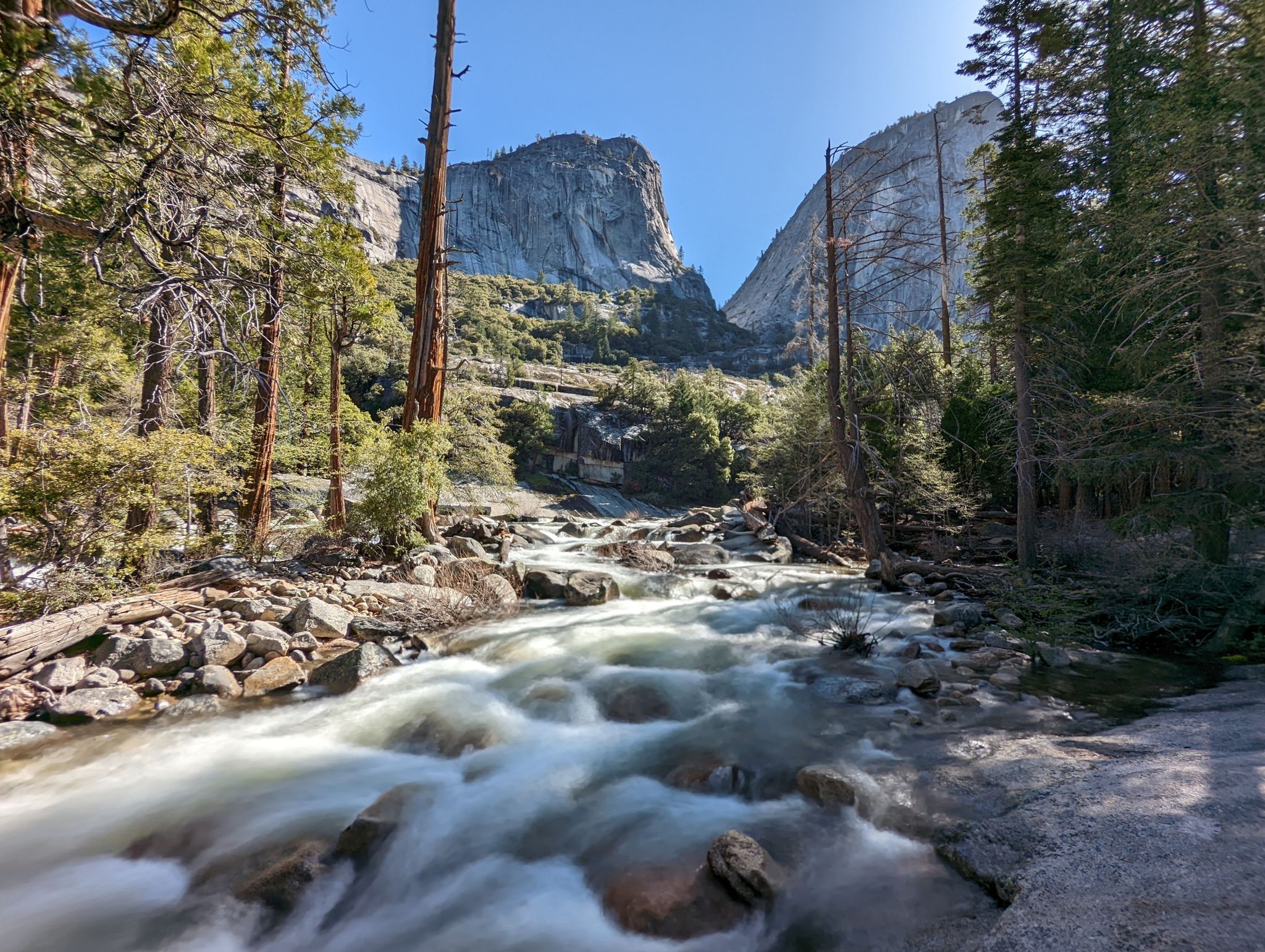 Rushing river flows through a forested valley with towering granite cliffs. - Vernal Fall and Clark Point Loop via Mist Trail and John Muir Trail