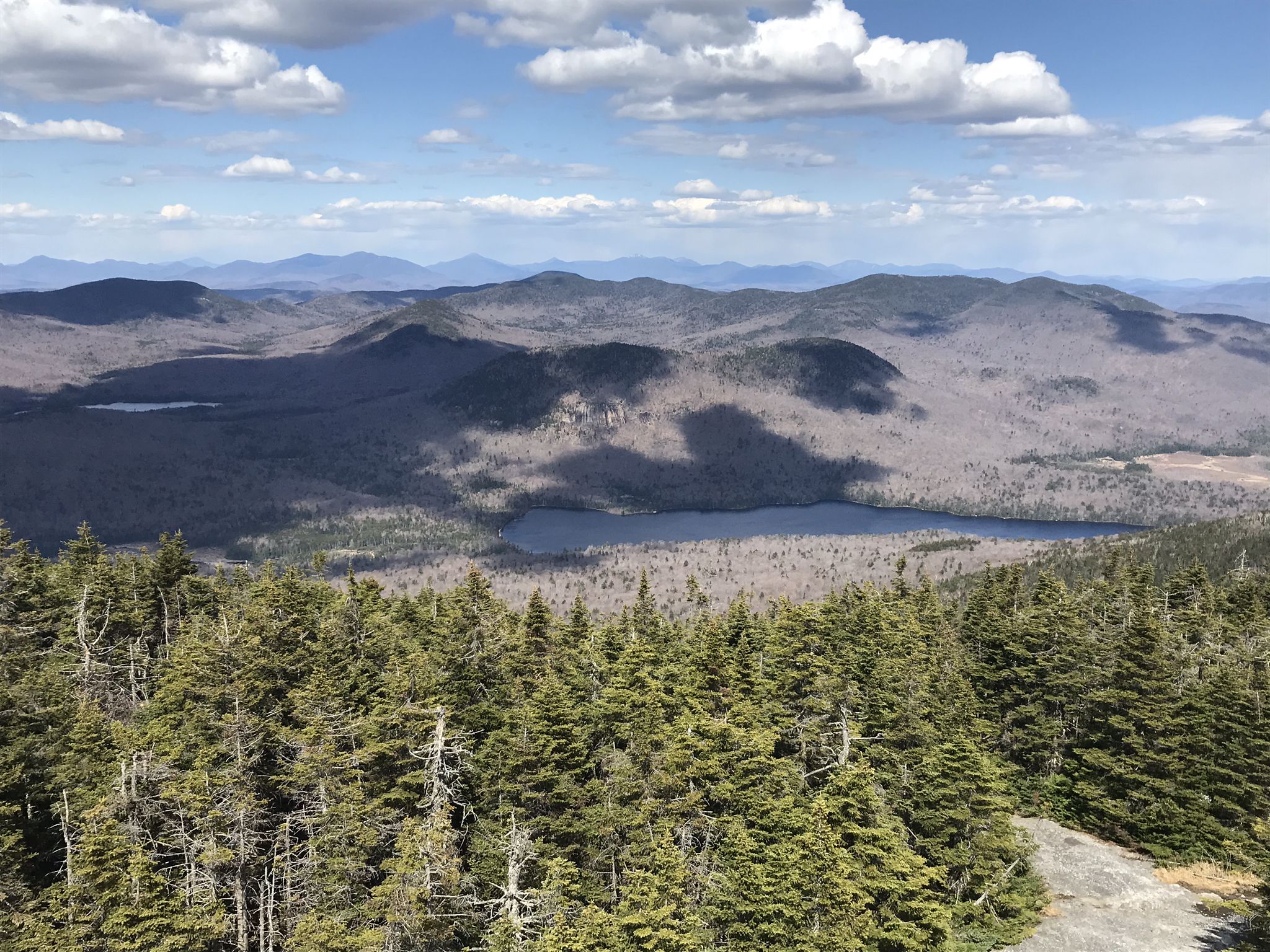Panoramic view of forested mountains, two lakes, under a partly cloudy sky. - Blue Mountain Trail