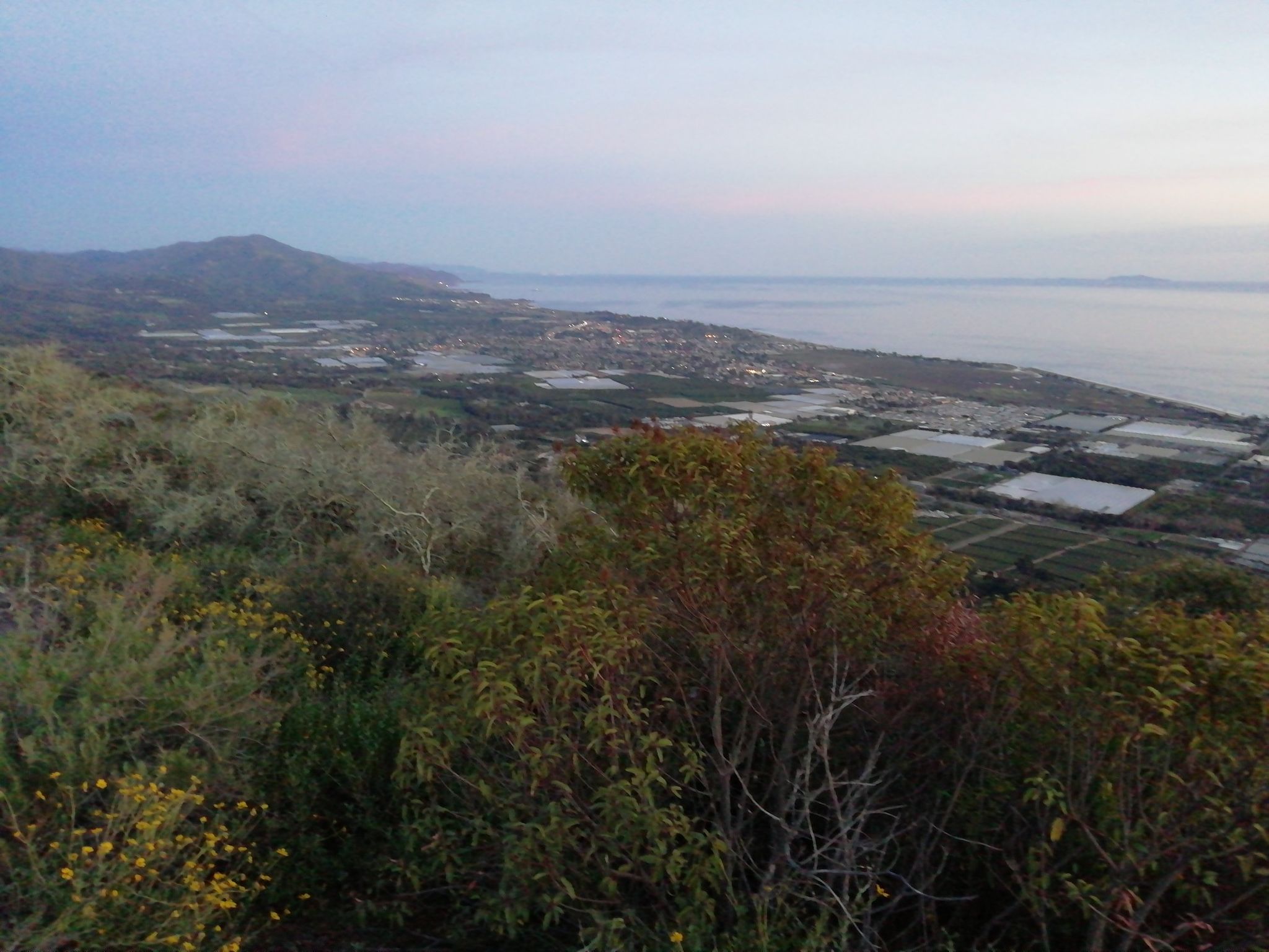Overcast view of a coastal valley with fields, a town, and distant mountains. - Toro Ridge Trail