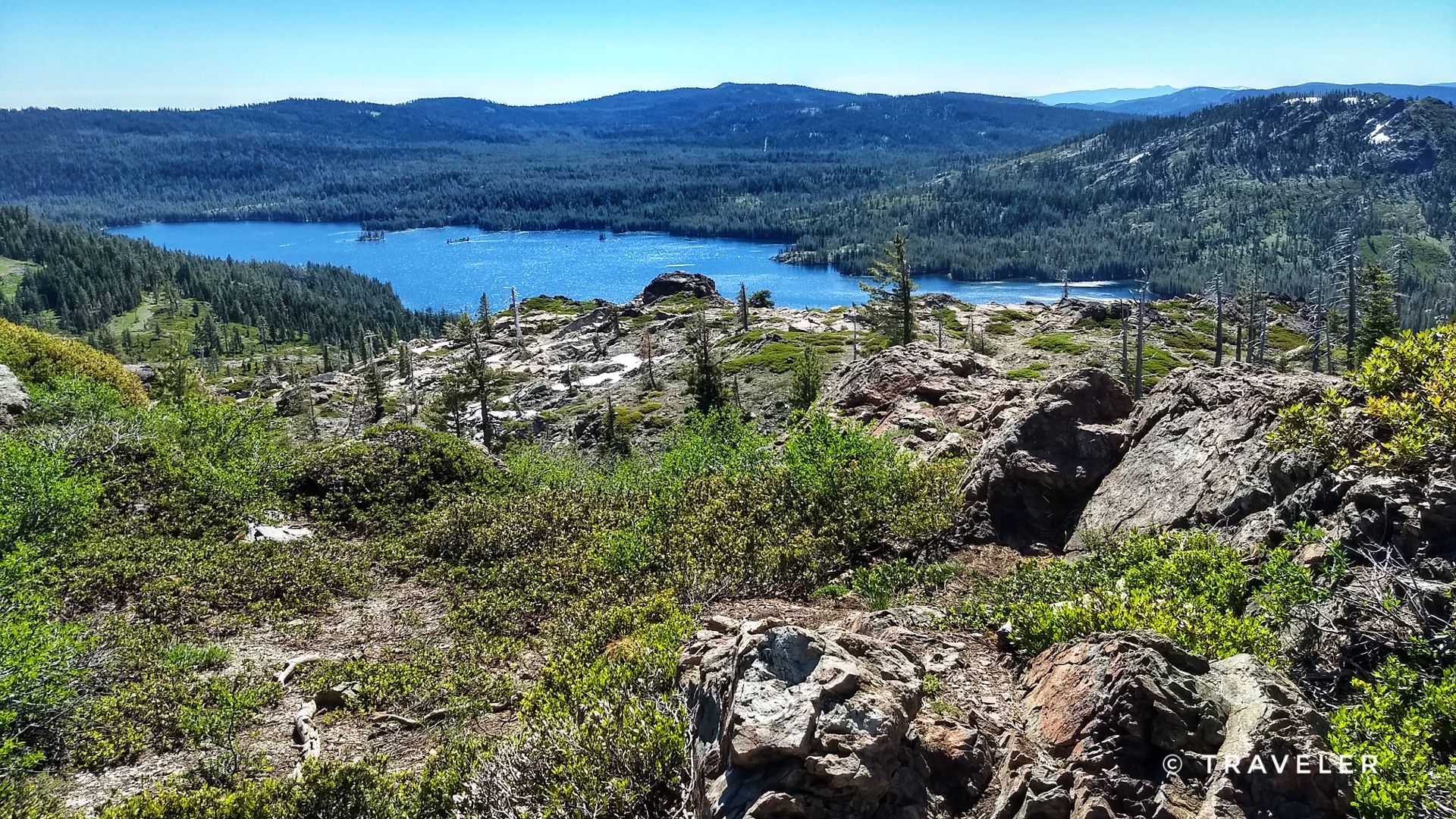 Blue lake nestled among green forests and rocky hills under a clear sky. - Bear Lakes and Round Lake Loop