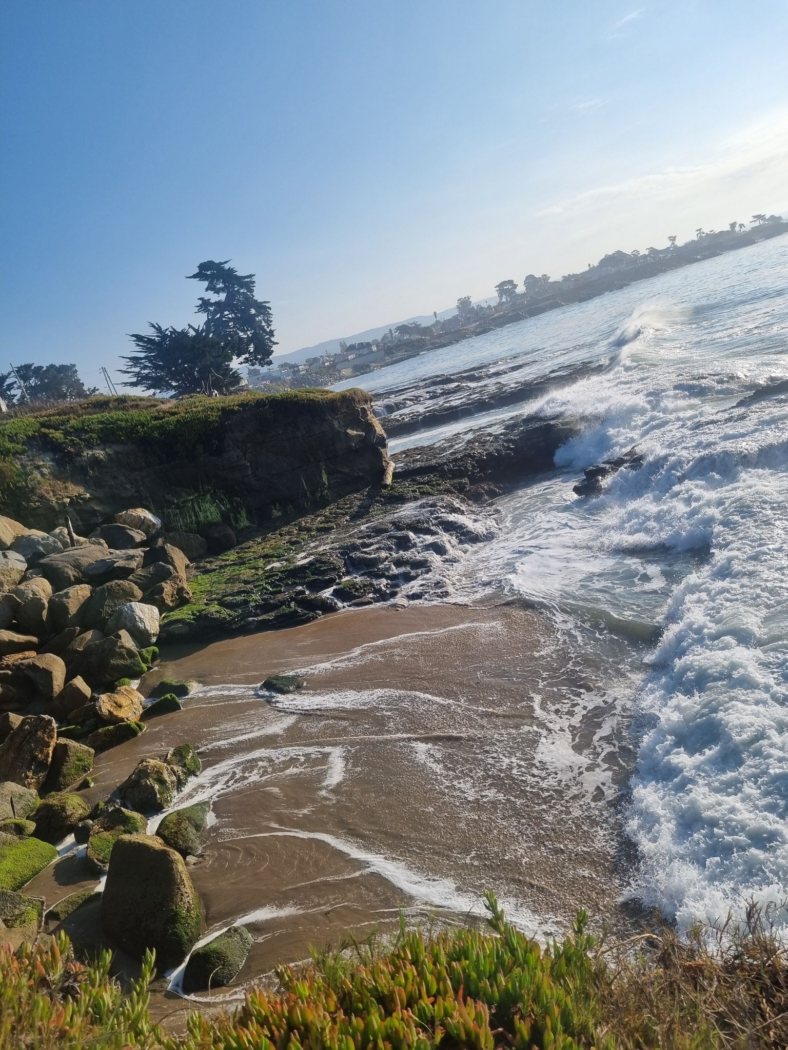 Sunny coastal view with waves crashing on a rocky, sandy shore. - Santa Cruz West Cliff and Riverwalk Loop