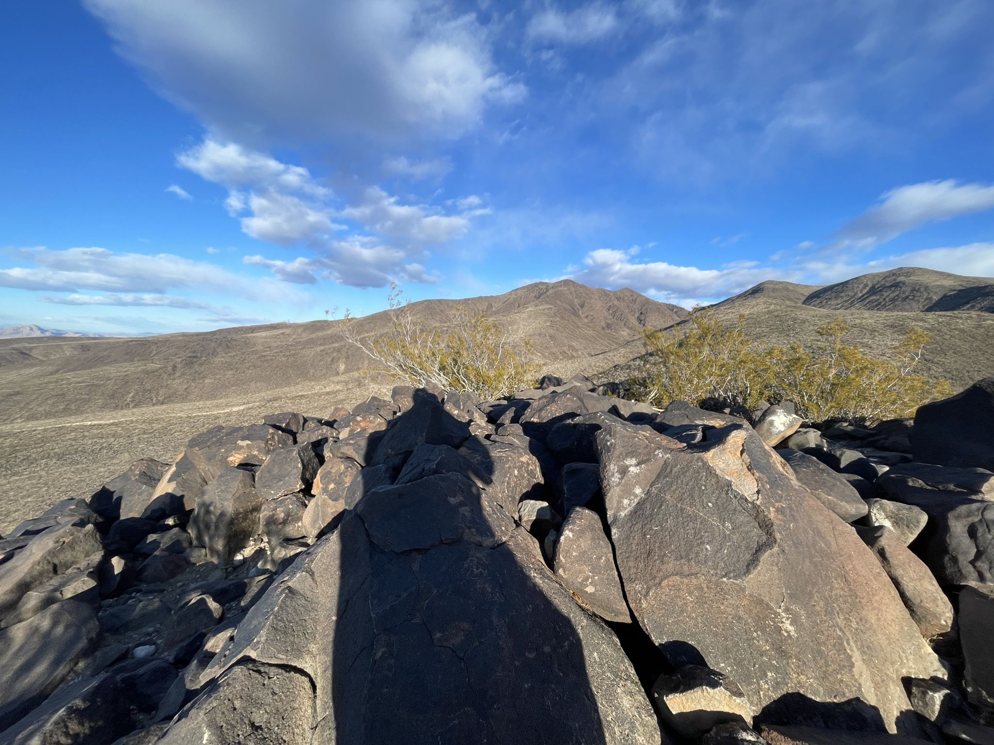 Dark rocks in the foreground with arid hills under a bright blue sky. - Park Peak Loop Trail