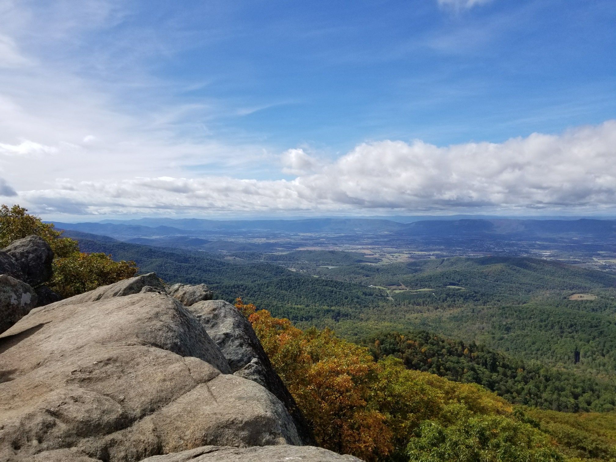Rocky outcrop overlooking a vast forested mountain landscape under a blue sky. - Marys Rock Summit Trail