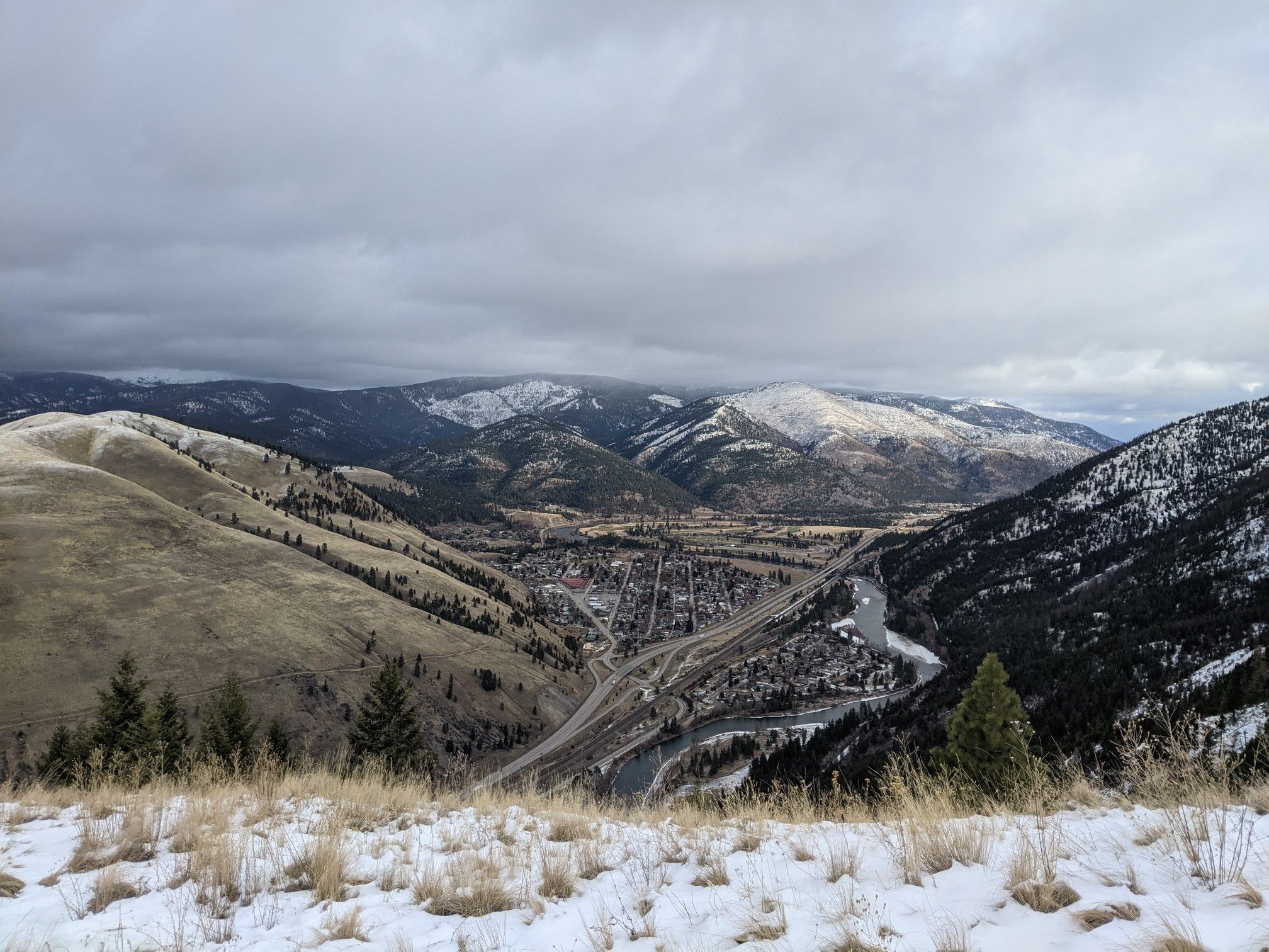 Wide view of a snowy mountain valley with a town and winding roads. - Mount Sentinel loop from Missoula