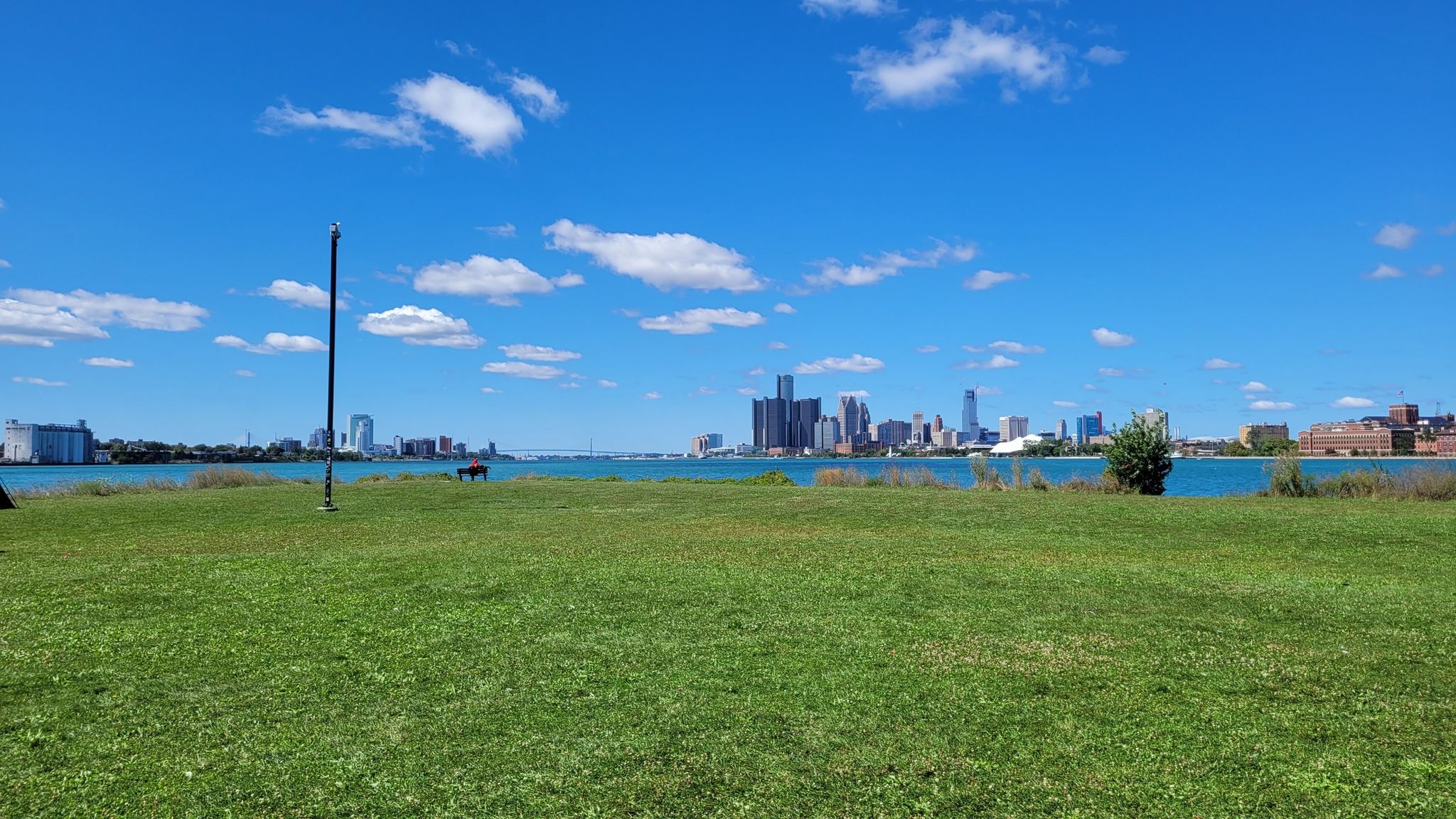Bright sunny day over a green field, water, and distant city skyline. - Ralph C. Wilson, Jr. Trail