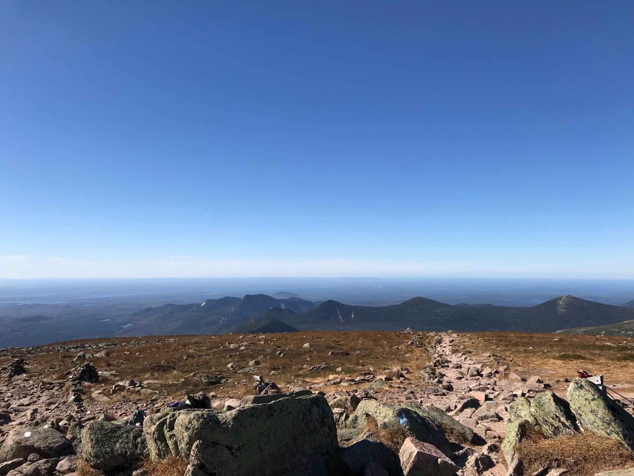 Vast, rocky mountain summit with distant hazy mountains under clear sky. - Abol Slide Trail