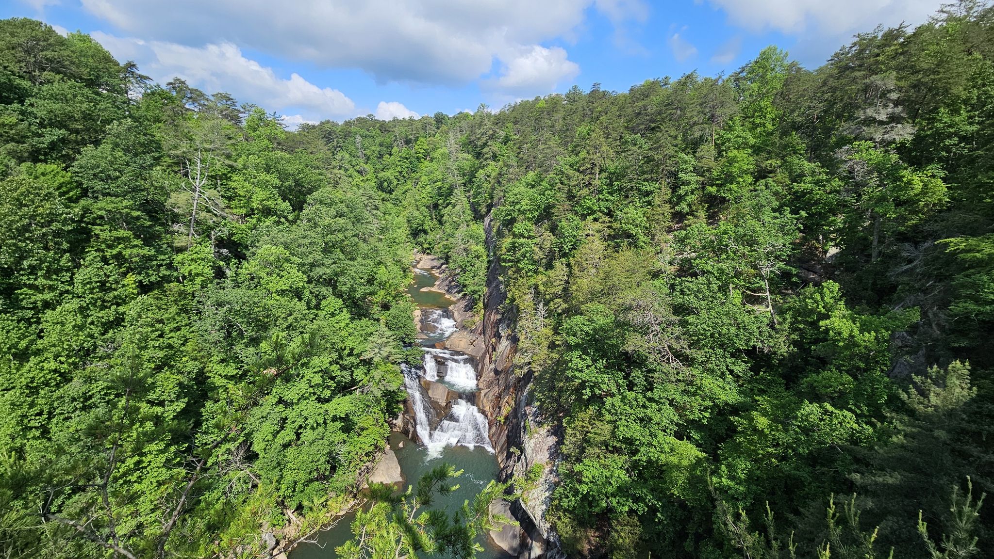 Waterfall cascading through a lush green canyon under a partly cloudy sky. - Hurricane Falls loop via North & South Rim Trails