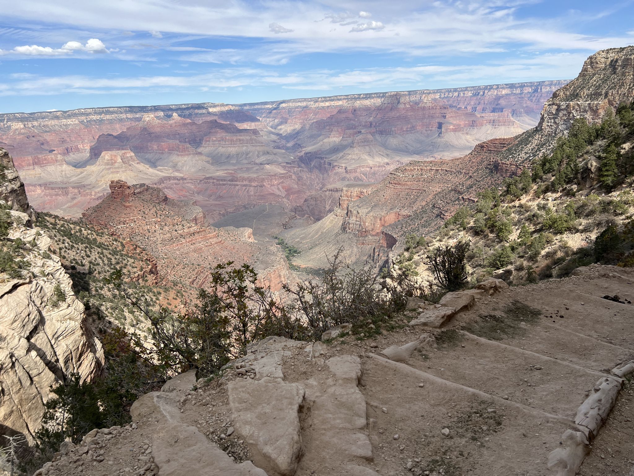 Canyon view from a dirt trail with steps, revealing distant layered formations. - 1.5 Mile Resthouse via Bright Angel Trail – Grand Canyon National Park