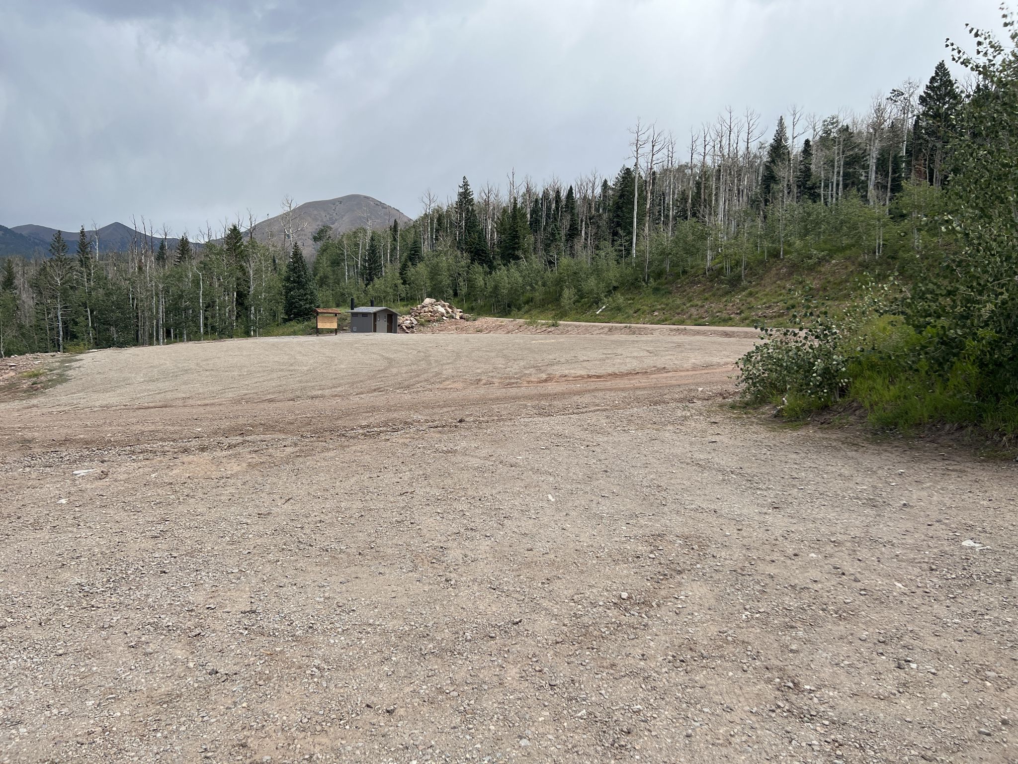 A large dirt clearing with distant mountains and a cloudy sky. - Clark Lake Loop