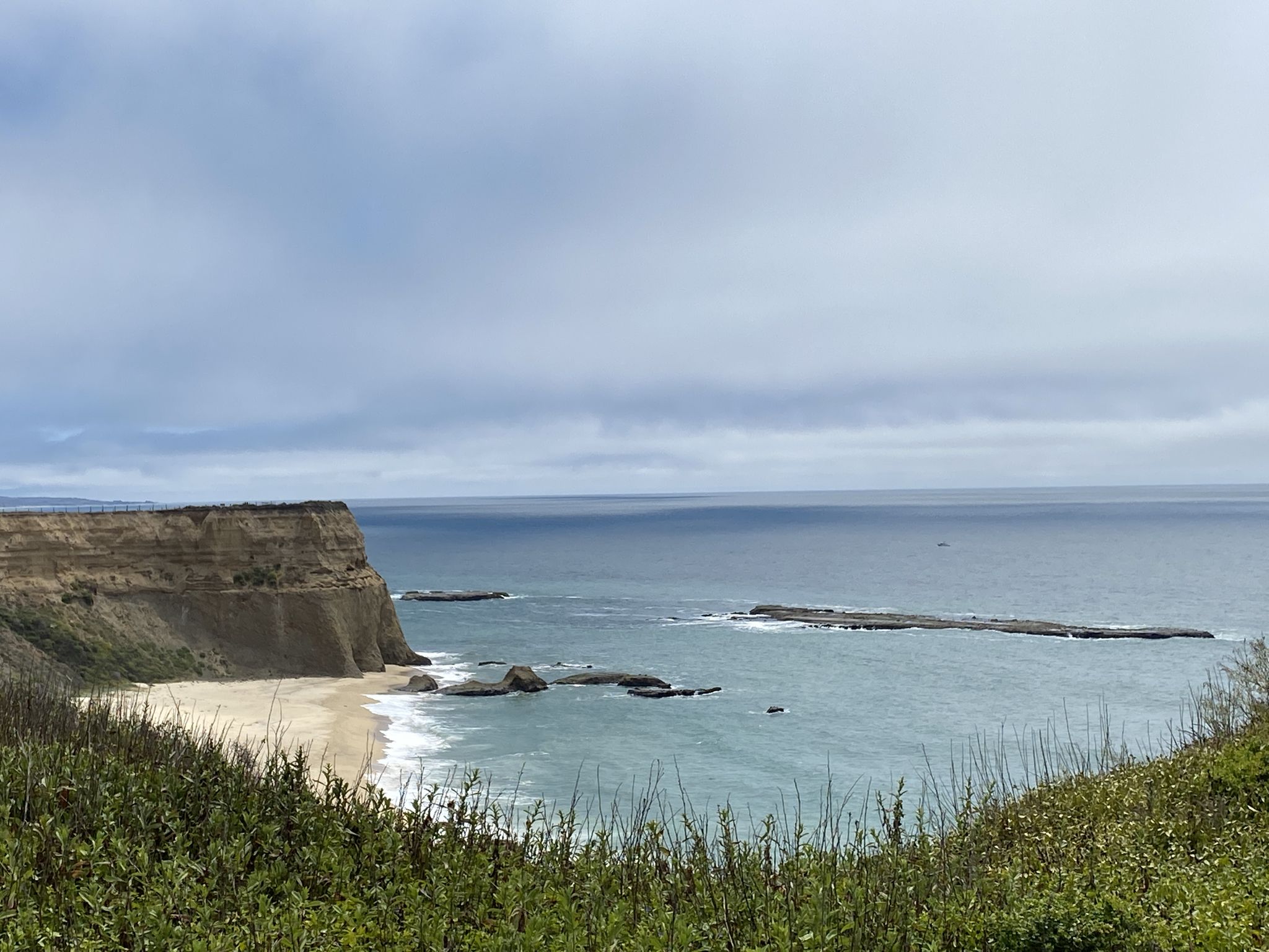 Distant sandy beach and ocean with sea stacks under a cloudy sky. - Whale Bone Beach loop from Seal Rock