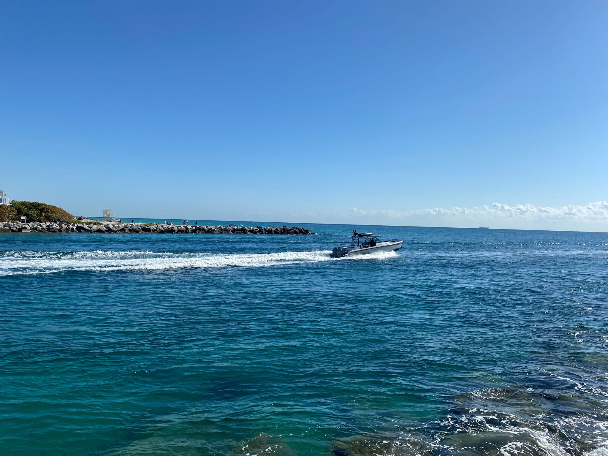 Speedboat on bright blue water, leaving a white wake, under clear sky. - Rotraut Color Sculptures loop from Surfside