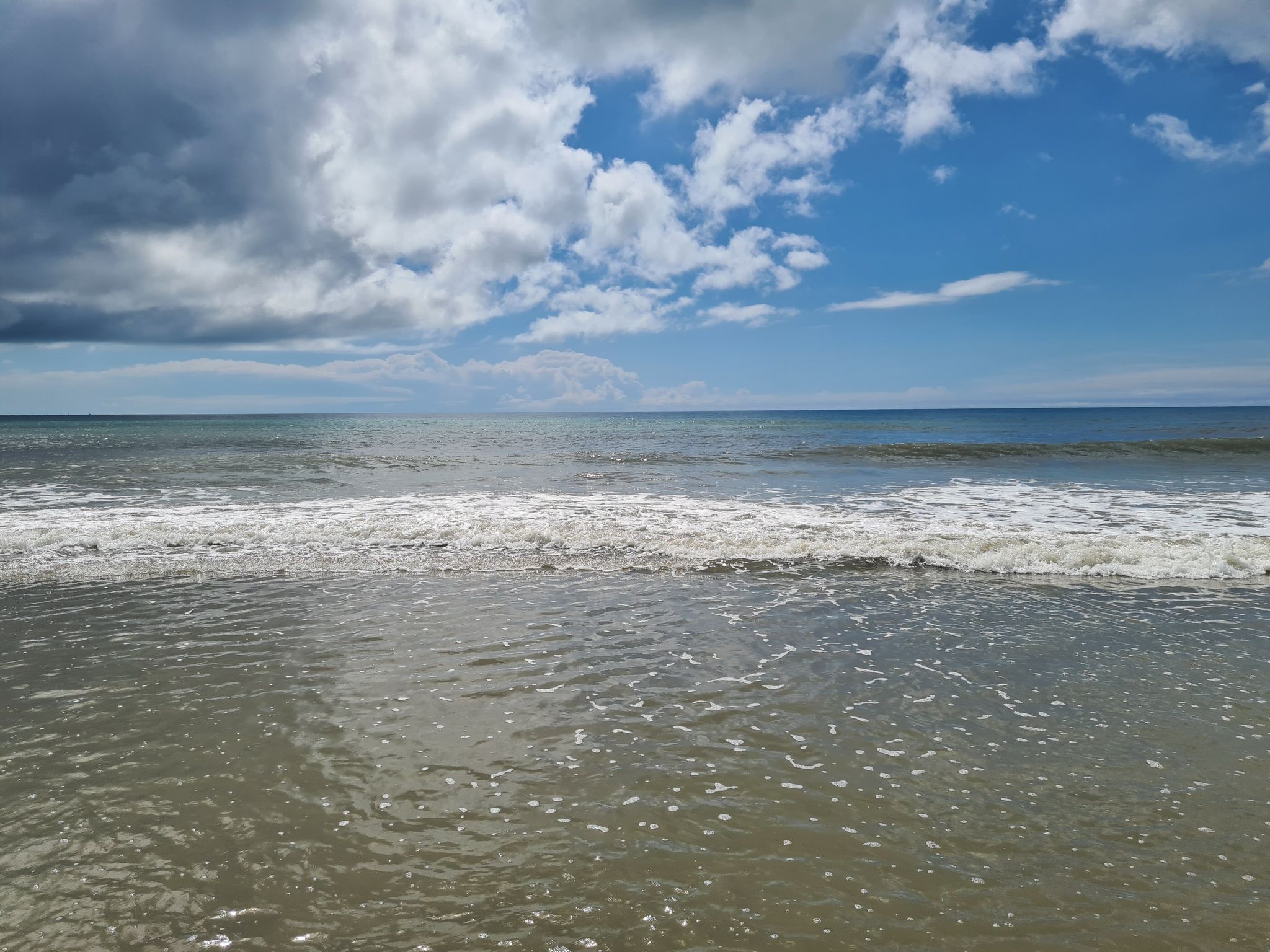 Ocean waves gently breaking on a sandy shore under a cloudy sky. - Cocoa Beach Pier loop