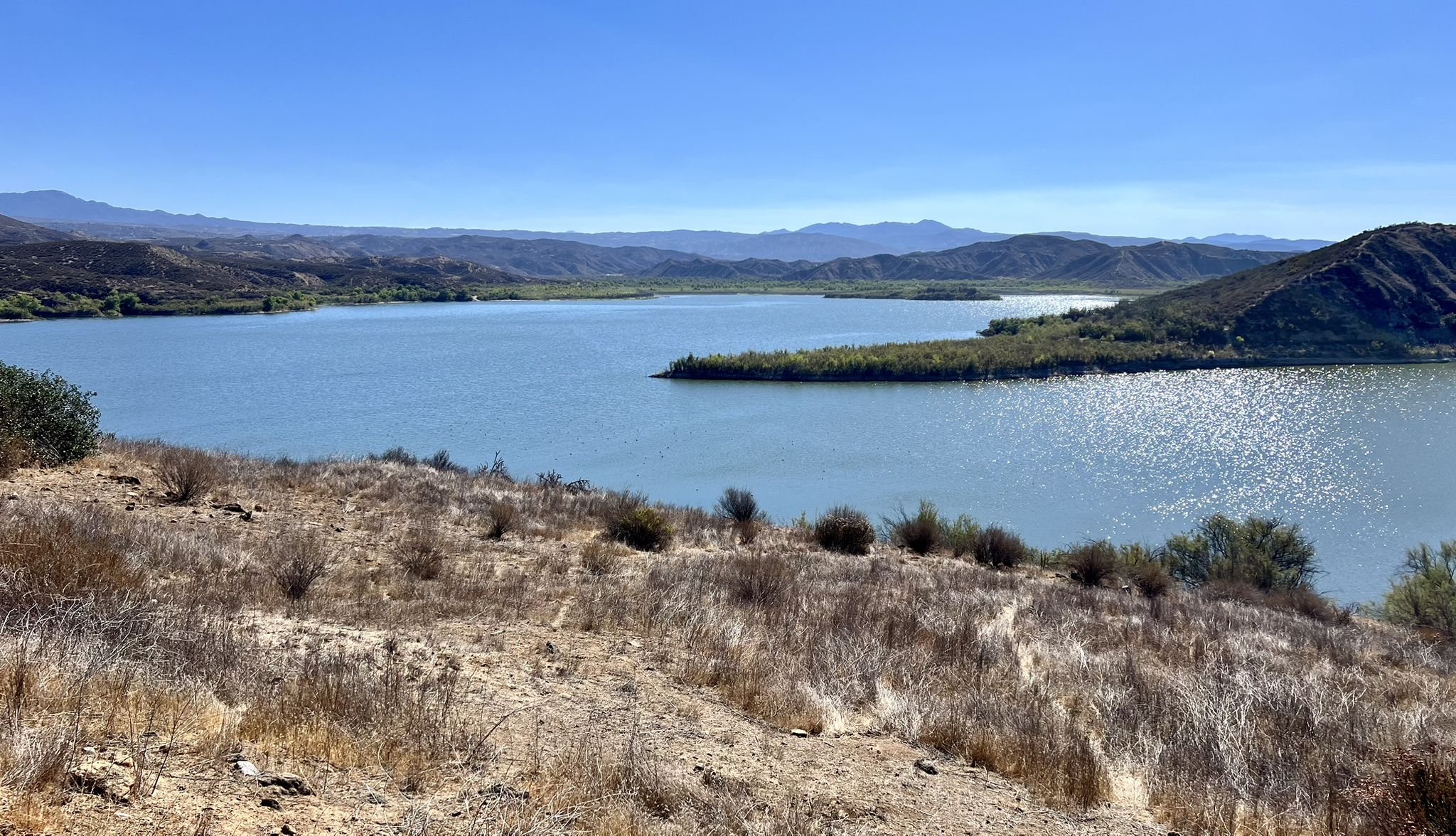 Wide shot of a calm lake surrounded by dry hills and distant mountains. - Vail Lake – Vail Lake loop from Dripping Springs
