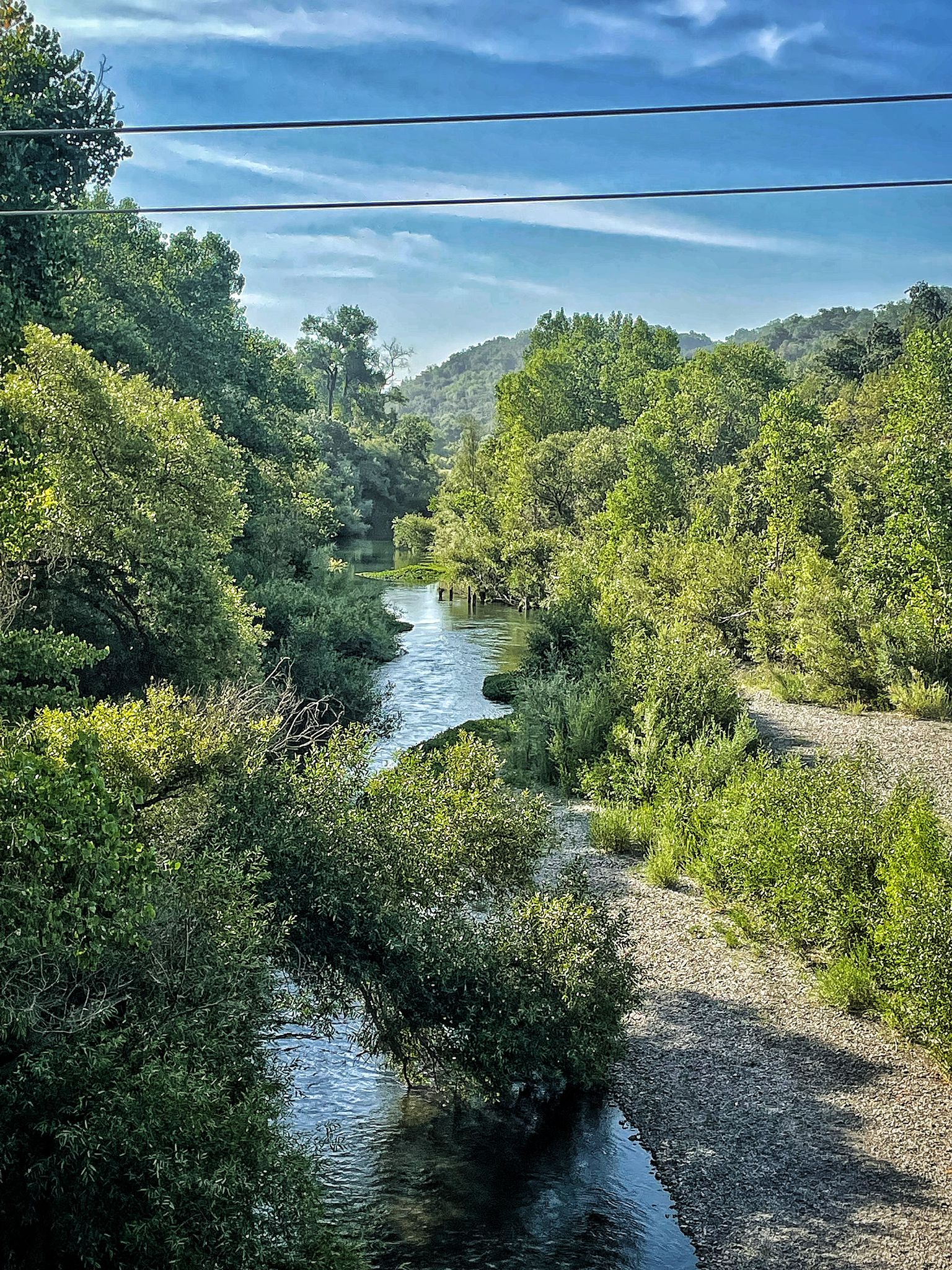 A winding river flows through a lush green valley on a sunny day. - Healdsburg Loop