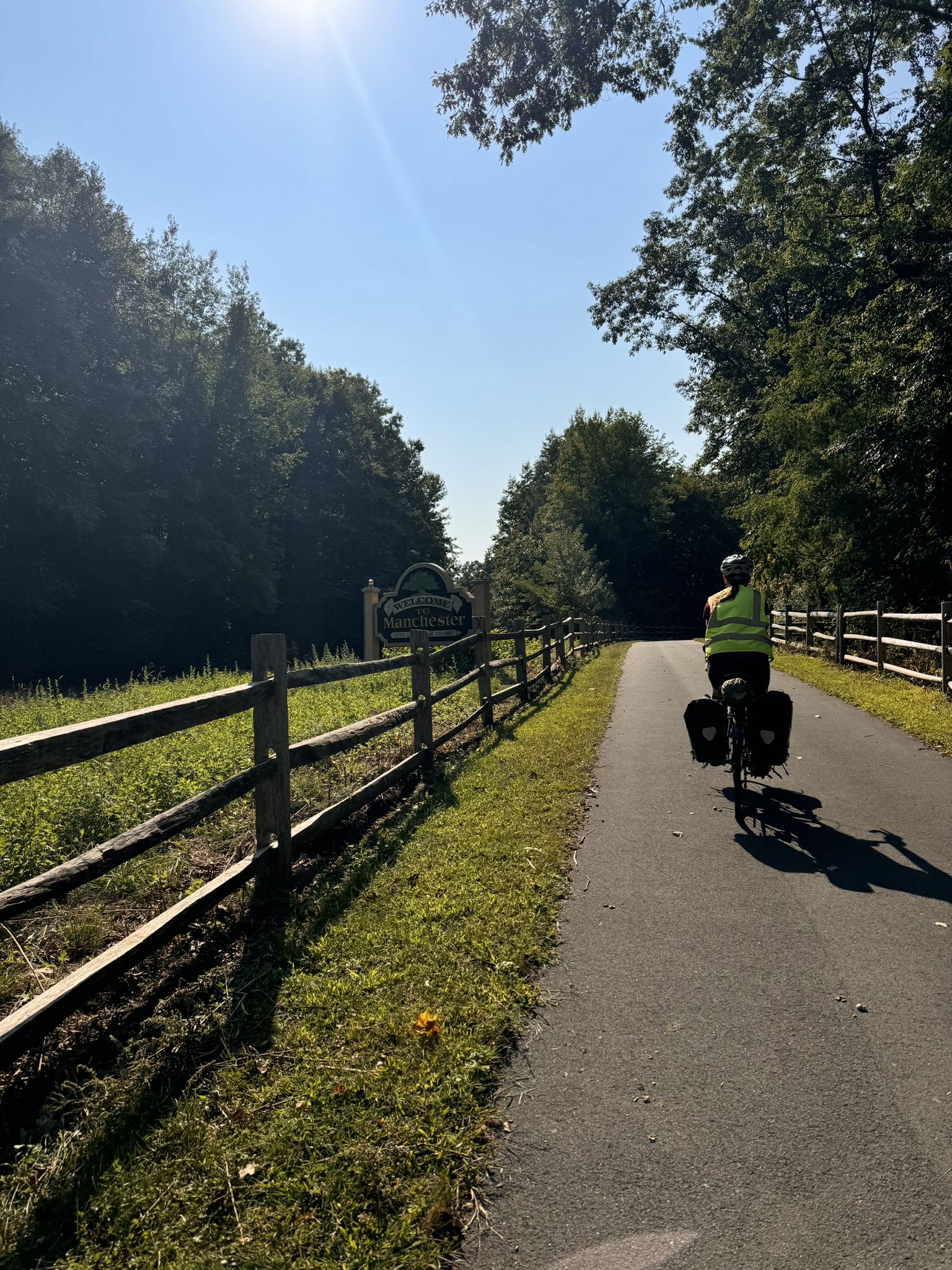 A person cycles on a paved path next to a wooden fence on a sunny day. - Gilead Cemetery – Gilead Congregational Church loop from Vernon