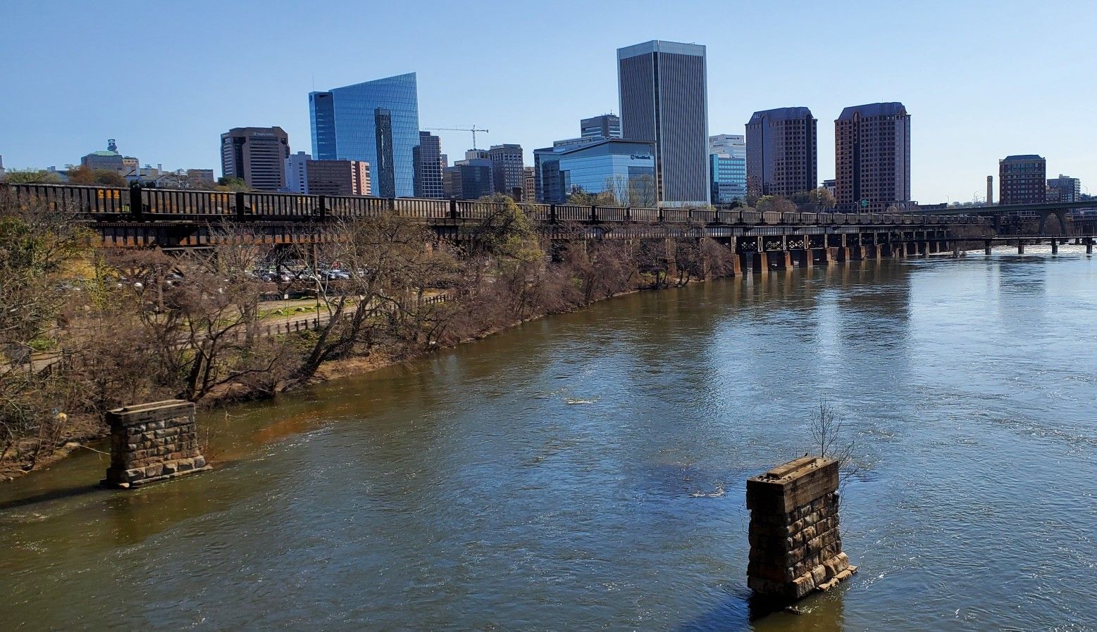City skyline with tall buildings reflected in a wide river with bridges. - Belle Isle and North Bank Trail Loop