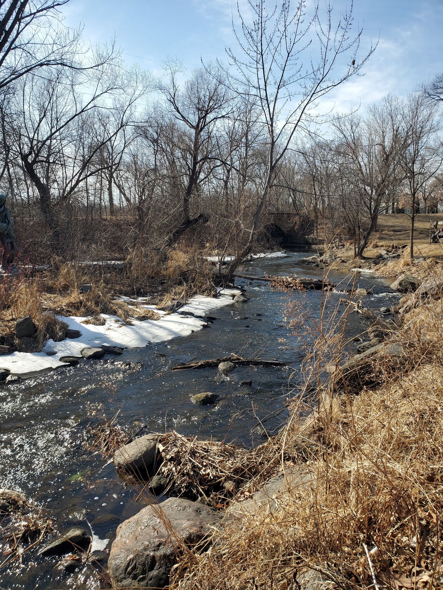 Small stream with ice and bare trees in winter, under a bright sky. - Minnehaha Falls – Hiawatha and Minnehaha Statue loop from 50th Street/Minnehaha Park