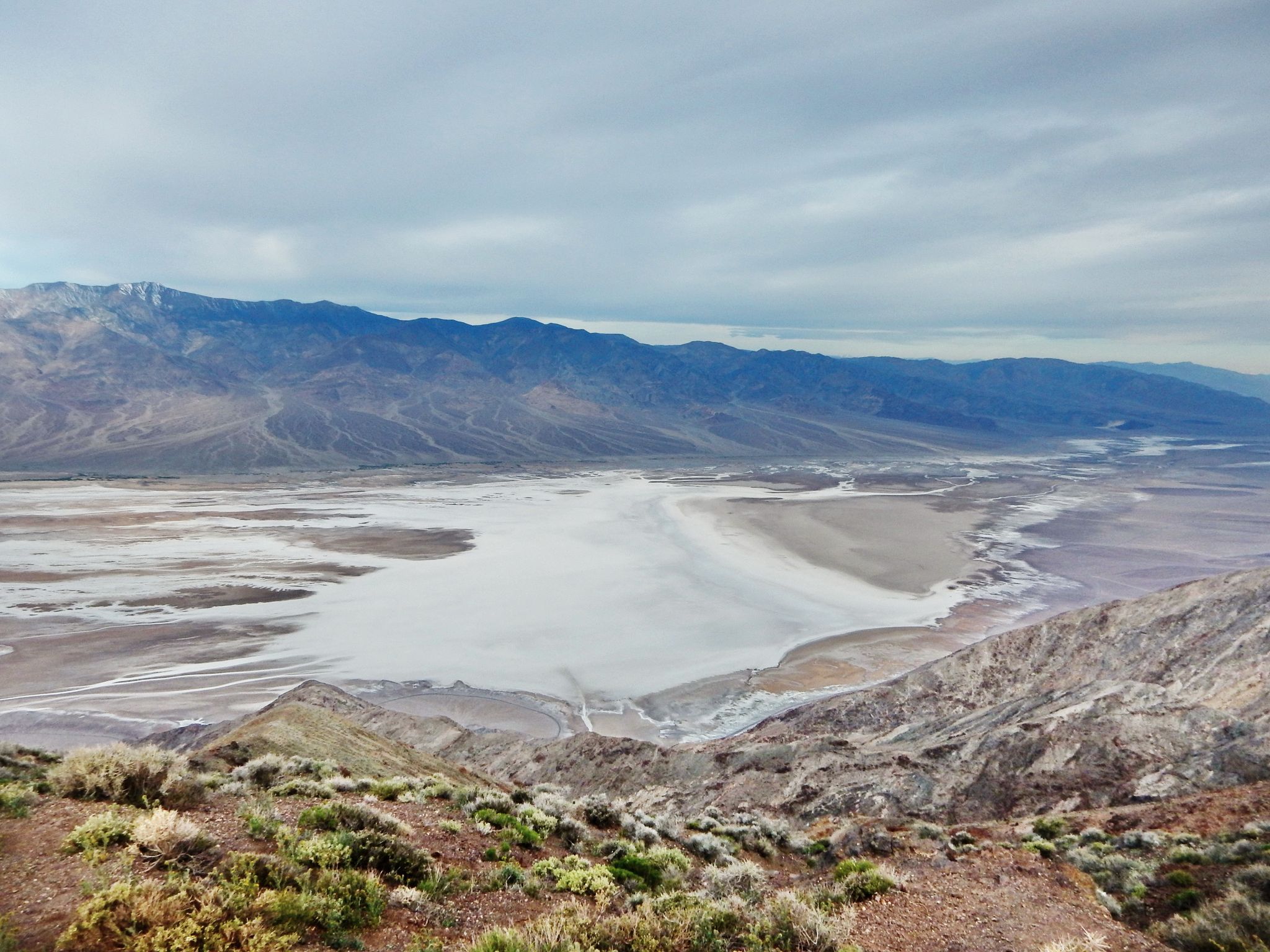 Wide desert valley with a large salt flat under an overcast sky. - Dante's View Trail