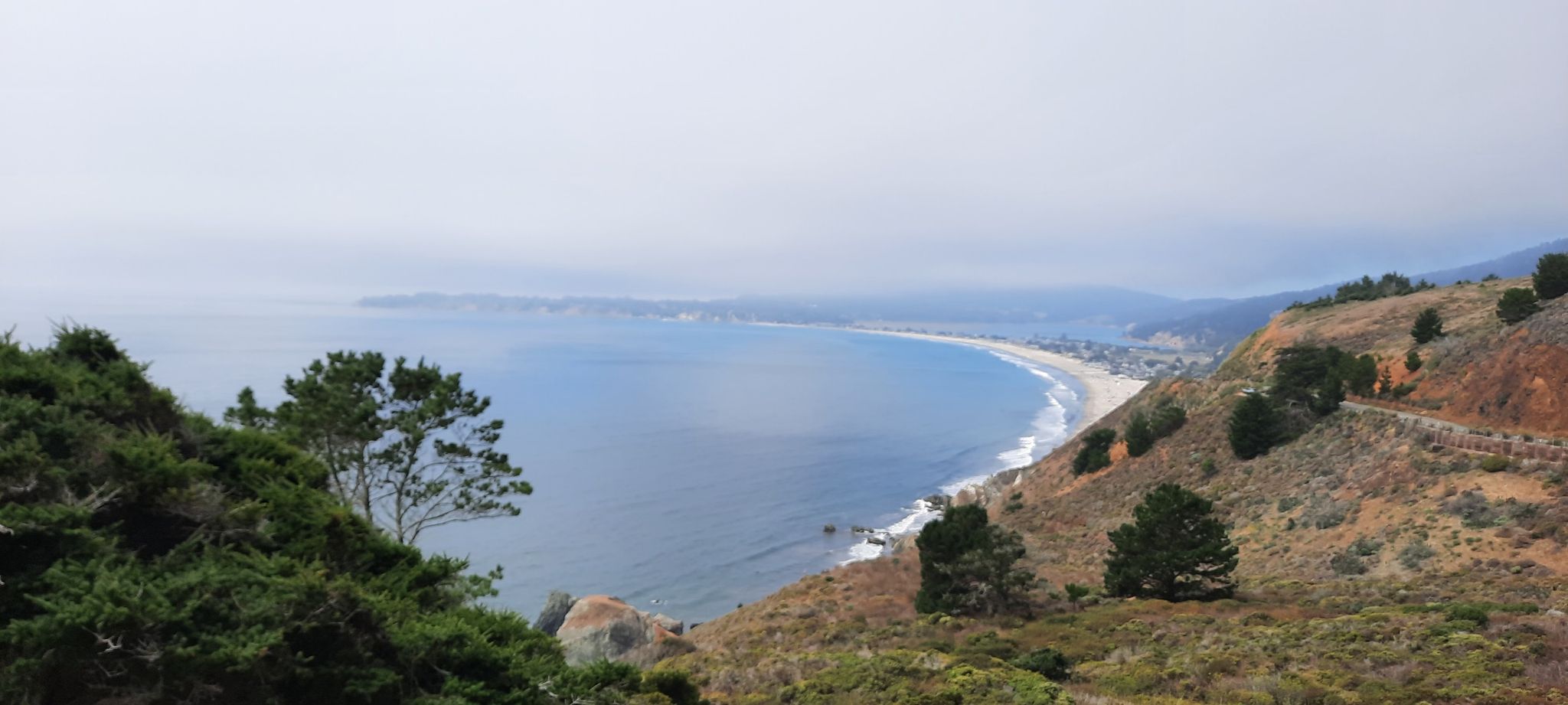 Sweeping view of a long sandy beach and hazy coastal hills. - Marin Coastal Bike Route