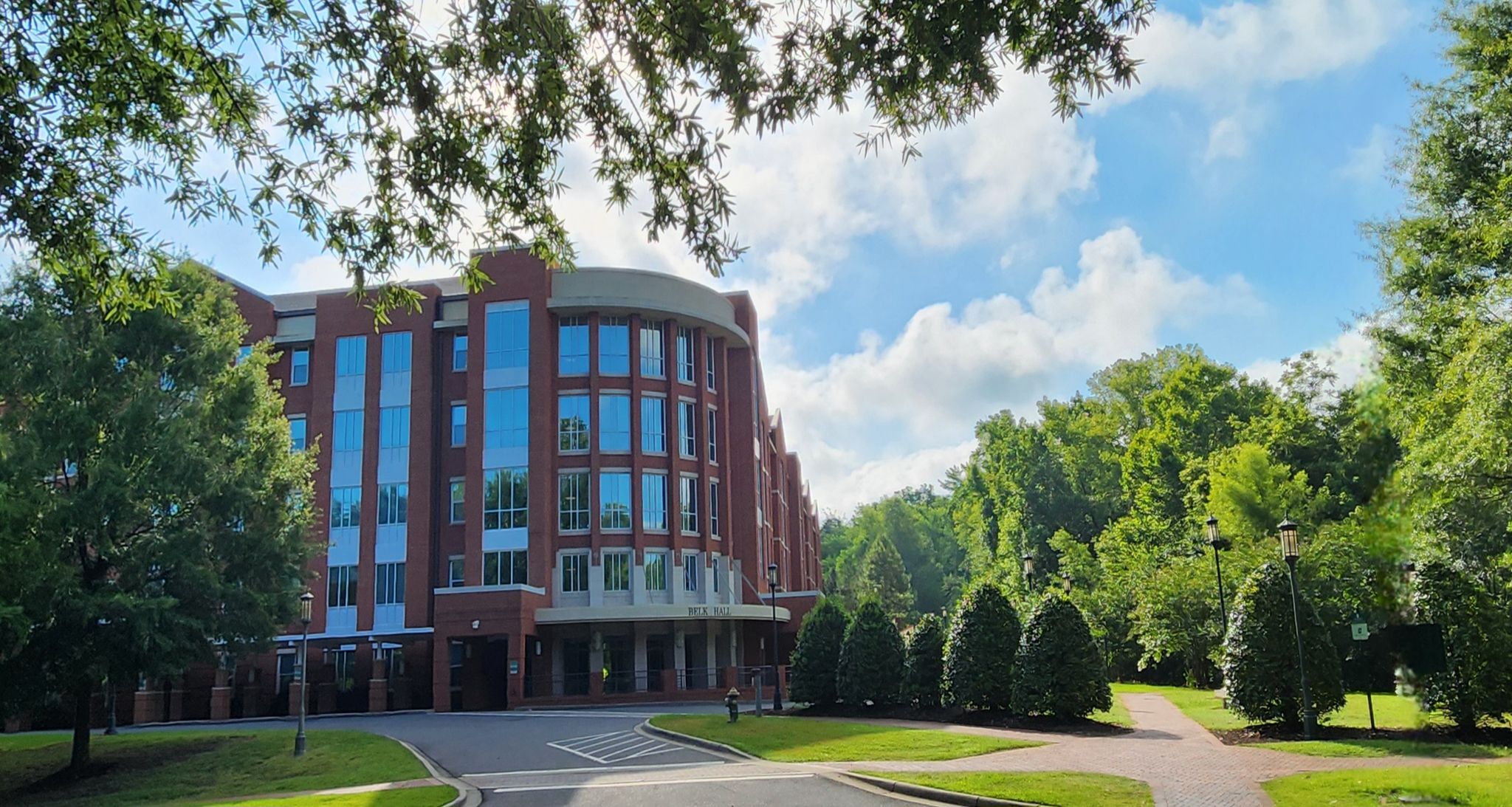 Large brick building surrounded by green trees under a bright, cloudy sky. - Mallard Creek Greenway – Mallard Creek Greenway loop from The University of North Carolina at Charlotte