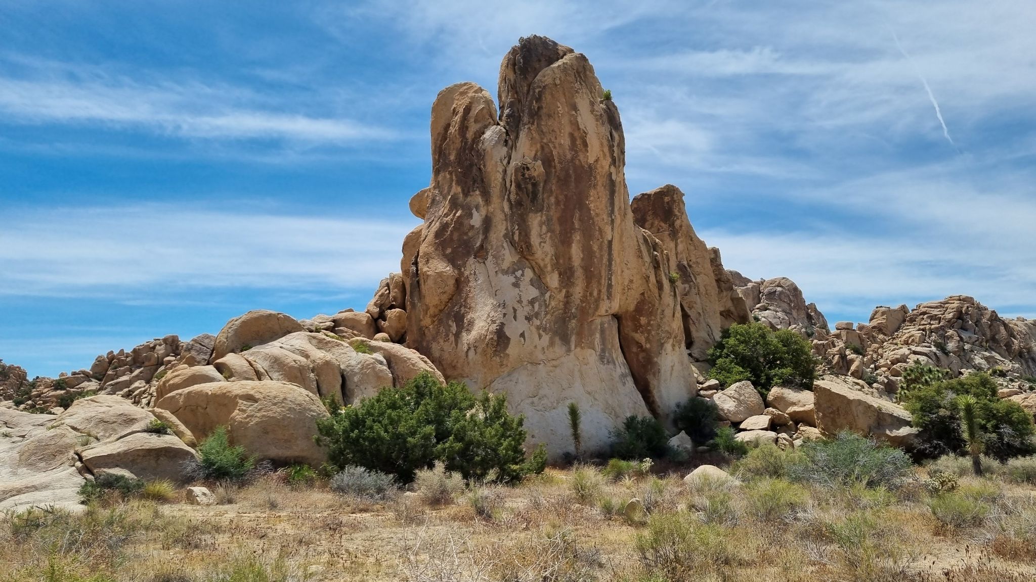 Massive rock formation dominates a desert landscape under a bright blue sky. - Joshua Tree National Park Scenic Drive via North Entrance