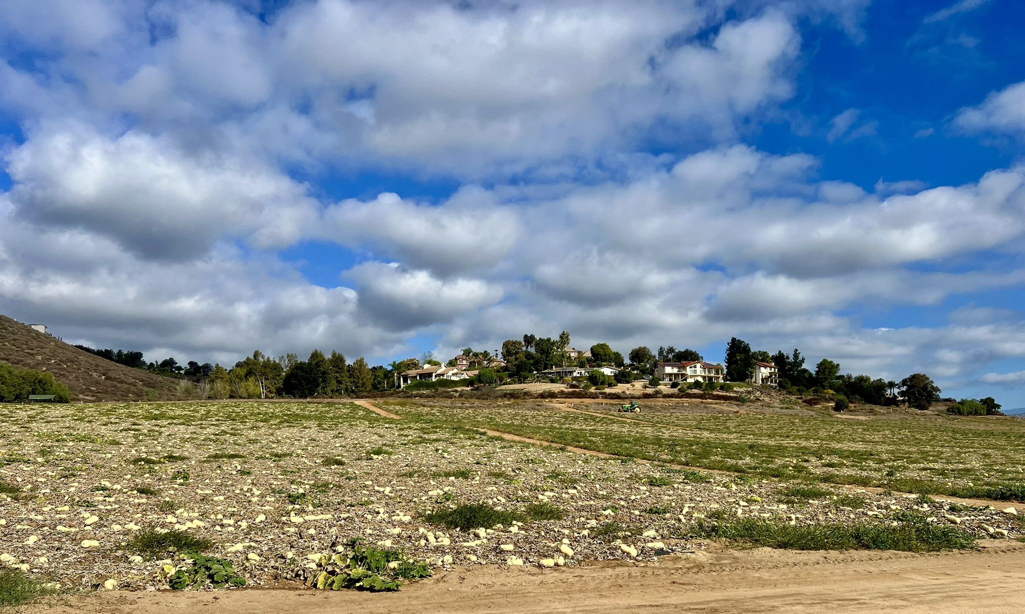 A rocky field with distant houses on a hill under a partly cloudy sky. - Mule Hill Trailhead – Mule Hill loop from San Dieguito River