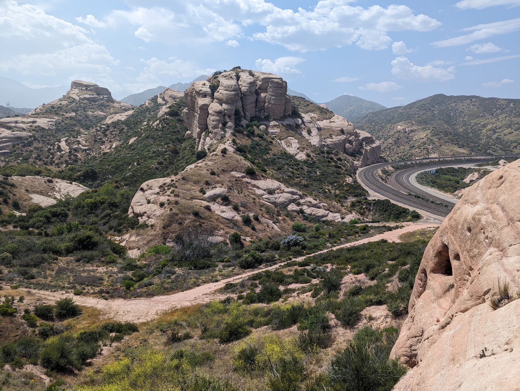 Arid landscape with large rock formations, scrub brush, and a winding road. - Pacific Crest Trail to Crowder Canyon