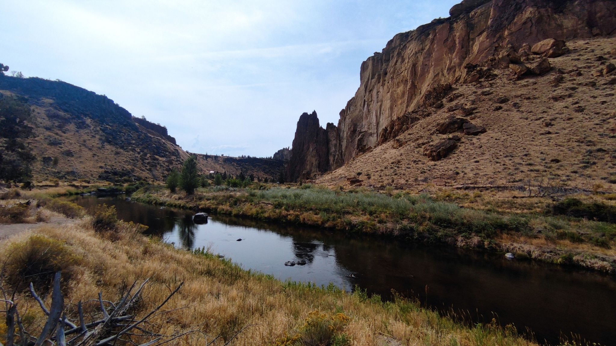 River flowing through a canyon with tall rock walls and dry grass. - Canyon and Homestead Trail Loop