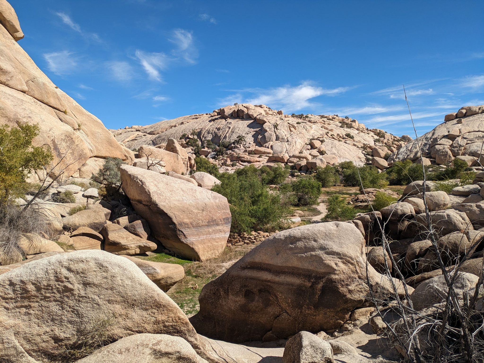 Large boulders and sparse green bushes under a bright blue sky. - Barker Dam Nature Trail