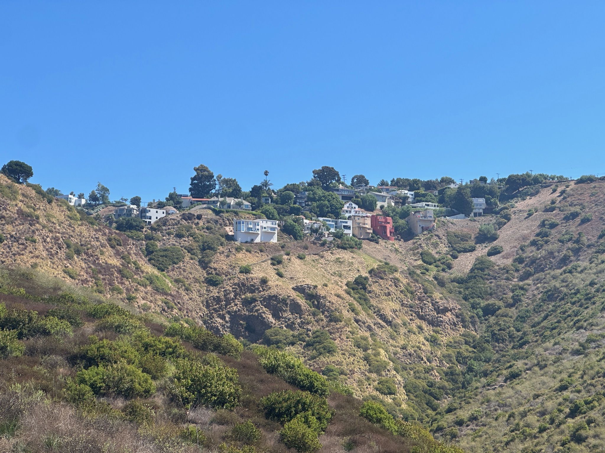 Houses on a distant hillside overlooking a valley under a clear sky. - TRW Loop Trail
