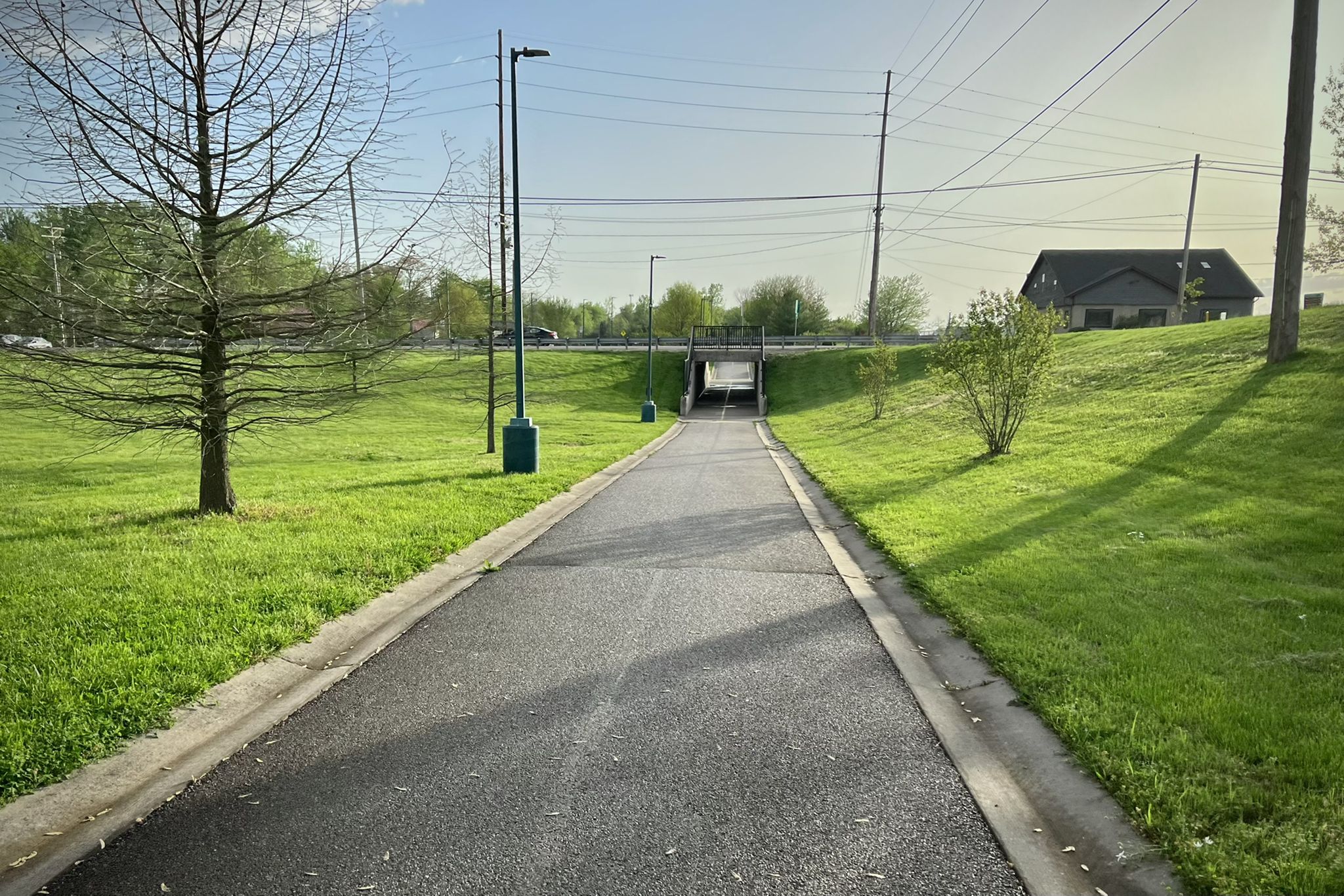 Paved path through green grass leading to an underpass on a sunny day. - Bike loop from Glen Carbon