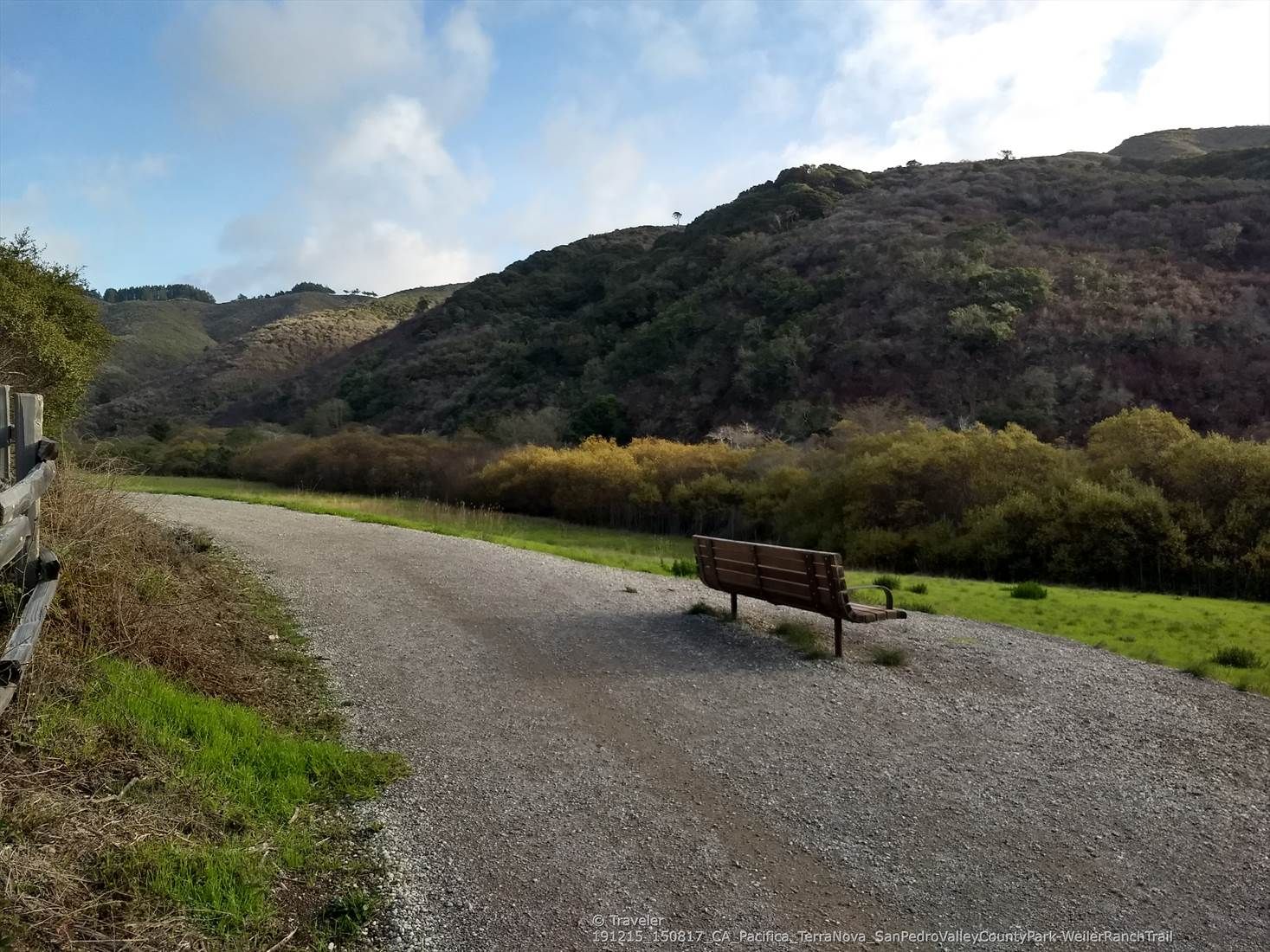Gravel path with a wooden bench, facing hills and green foliage. Bright sky. - Weiler Ranch and Valley View Trail Loop