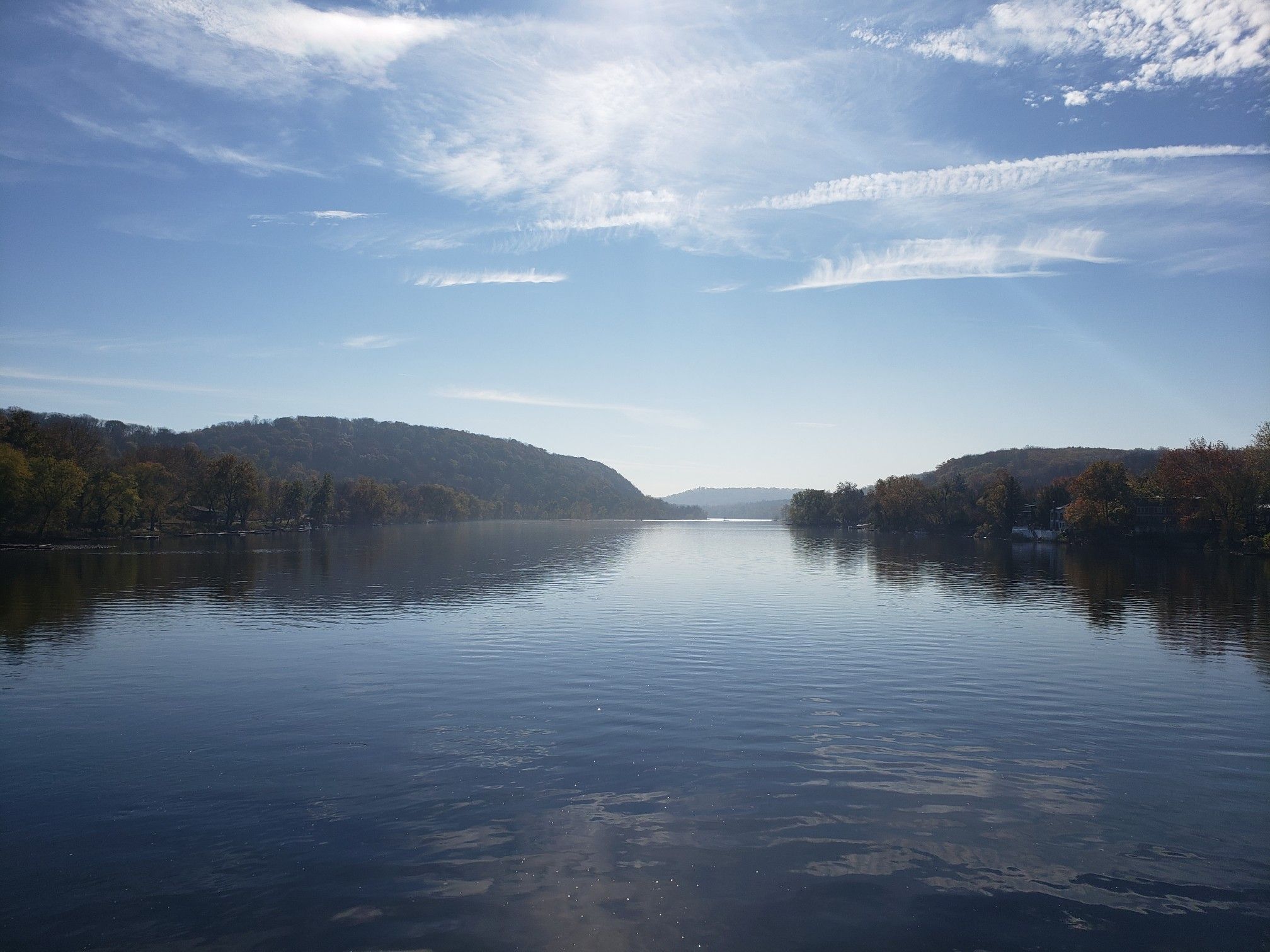 A wide, calm river reflects a bright sky between two forested hills. - New Hope – View of the Delaware River loop from New Hope