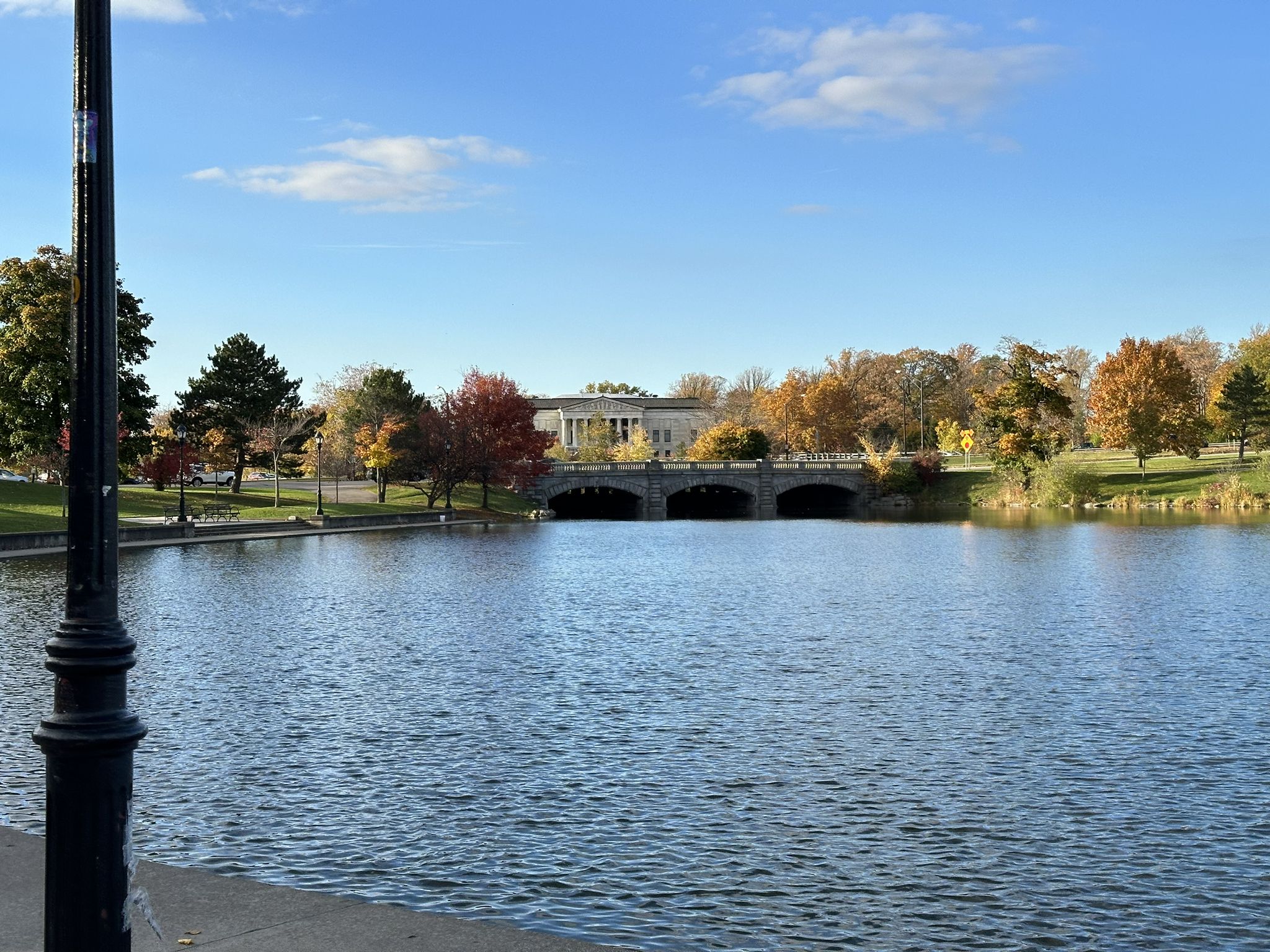 Calm lake with a stone bridge and autumn trees under a bright sky. - Delaware Park loop