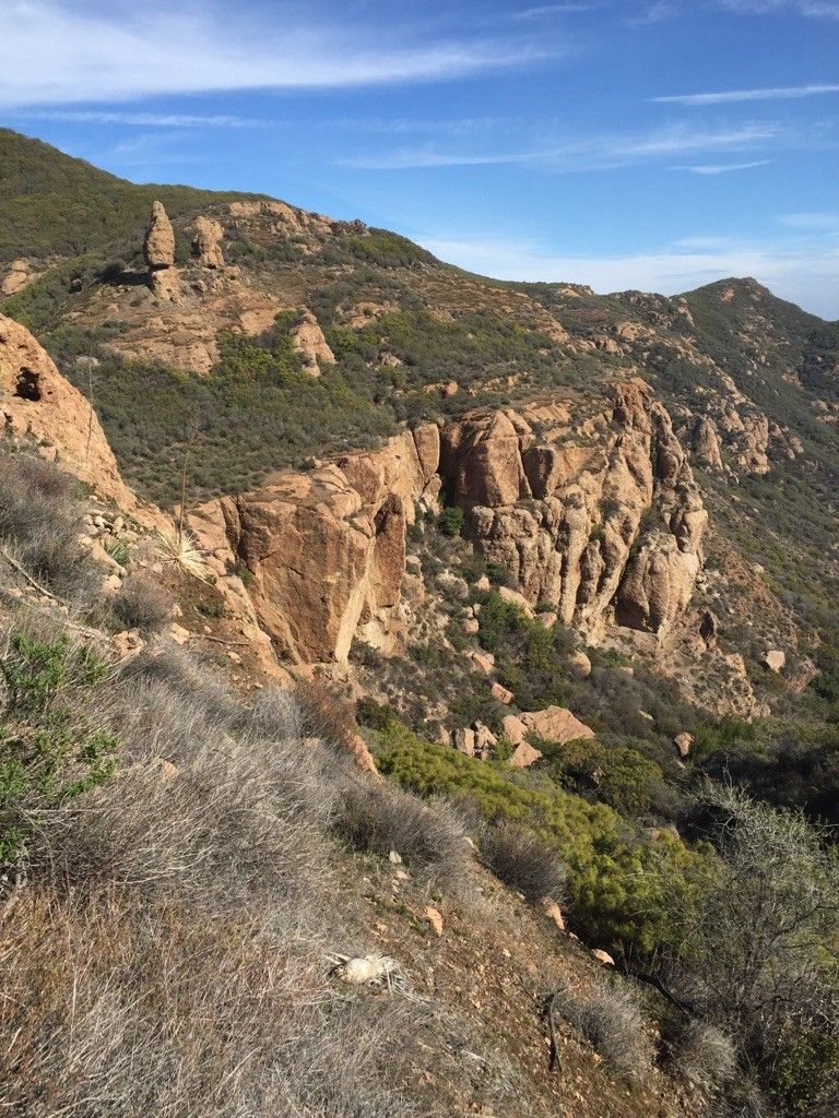 Steep, rugged rock formations and brush-covered hillsides under a clear sky. - Sandstone Peak Trailhead – Split Rock Picnic Area loop from Circle X Ranch