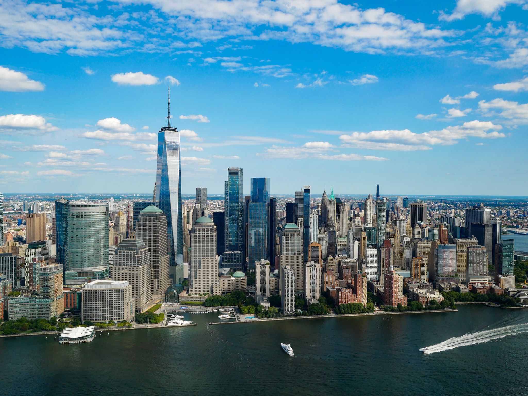 Aerial view of a dense city skyline along a river with boats. - Brooklyn Waterfront and Ocean Parkway Loop
