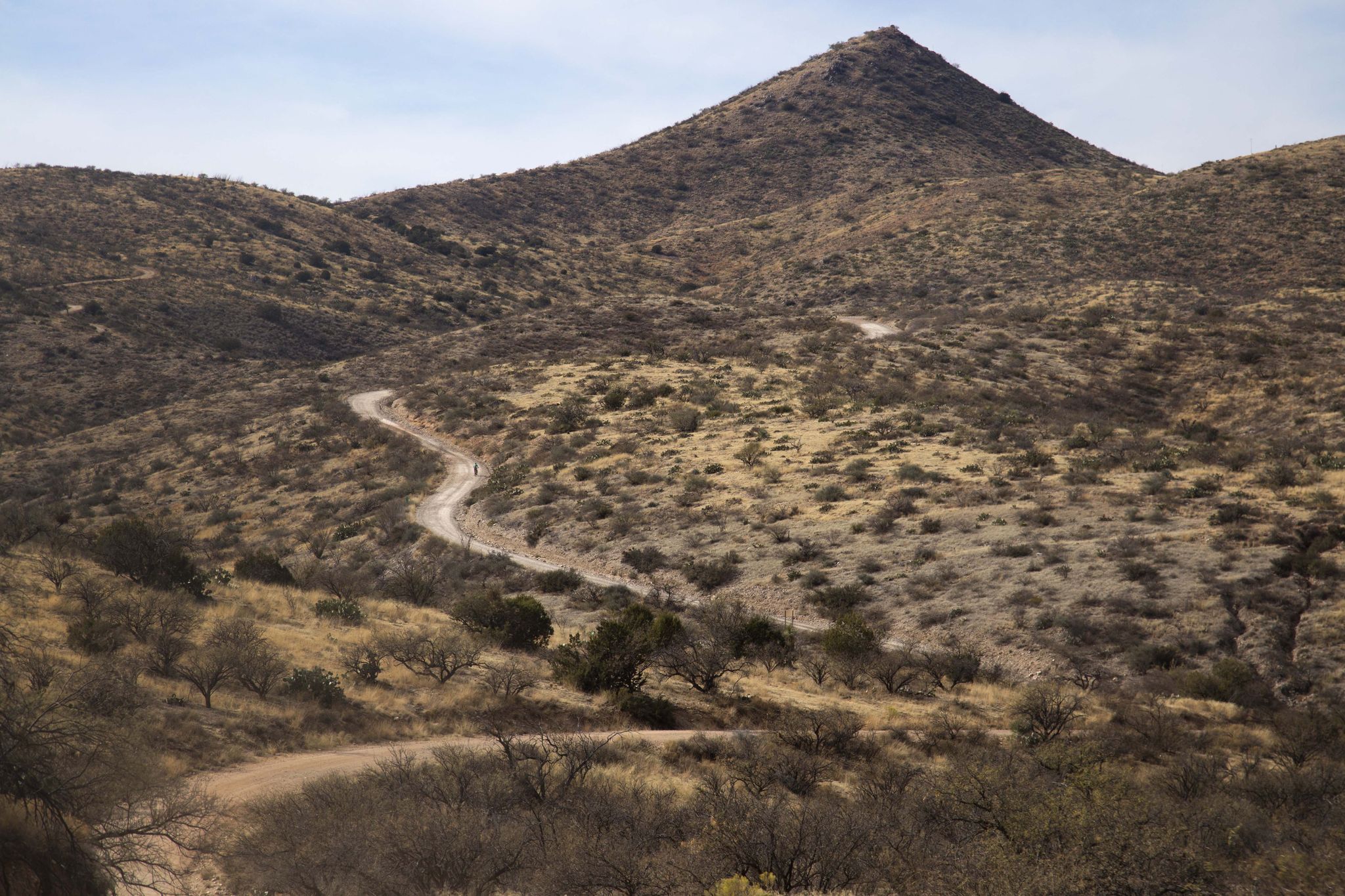 Winding dirt road ascends a dry, rocky mountain under a bright sky. - Chiva Falls Loop via Arizona Trail