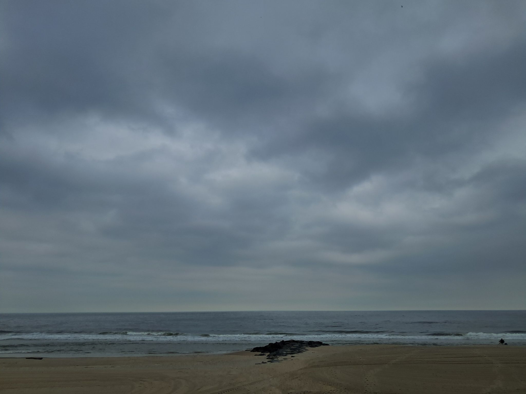 Dark overcast sky over a wide sandy beach and gray ocean. - Shrewsbury River – Sea Bright Bridge loop from Shrewsbury