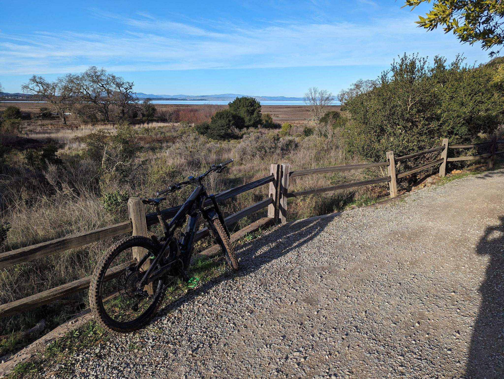Mountain bike leaning on a wooden fence next to a gravel path. - Back Ranch Meadows Loop