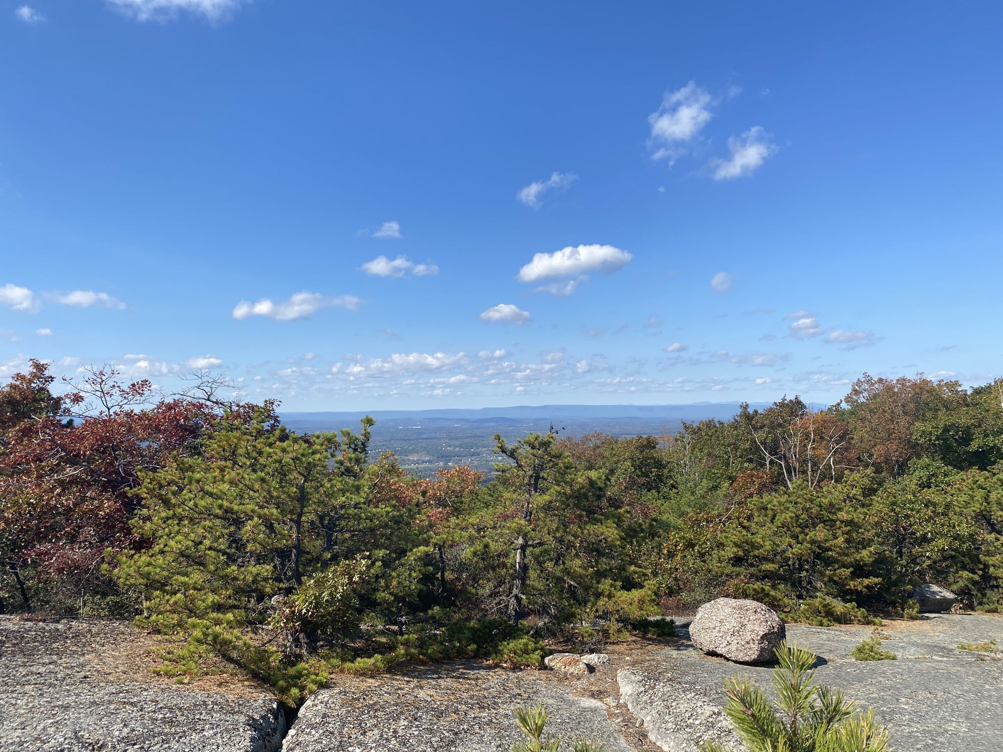 Sunny panoramic view from a rocky outcrop over a vast forested landscape. - Schunnemunk Mountain via Jessup Trail